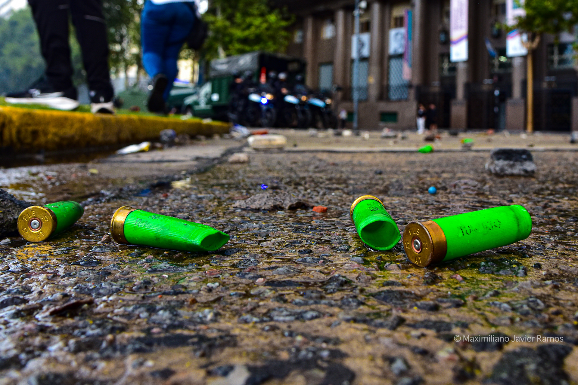 Cartuchos usados de armas policiales en la acera, cerca del Congreso Nacional. Al fondo, las luces de las motocicletas antidisturbios. // Used cartridges from police weapons on the pavement in the vicinity of the National Congress. In the background, the lights of riot police motorcycles.