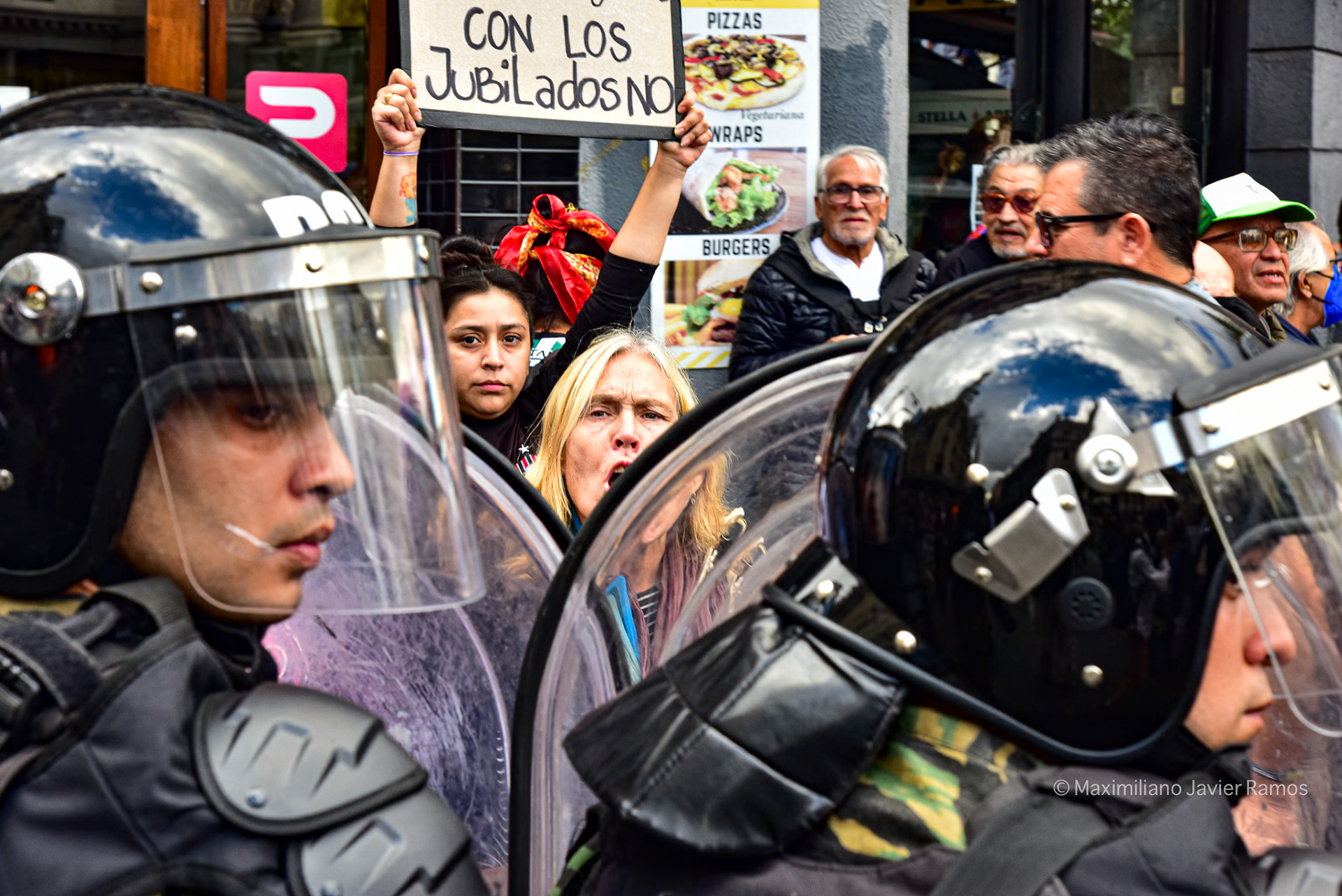 Una mujer grita al cordón policial que separa a los manifestantes del Congreso Nacional. Detrás de ella, un cartel dice: "Eso con los jubilados no". // A woman shouts at the police cordon between the protesters and the National Congress. Behind her is a sign that reads: "Not that with retirees."