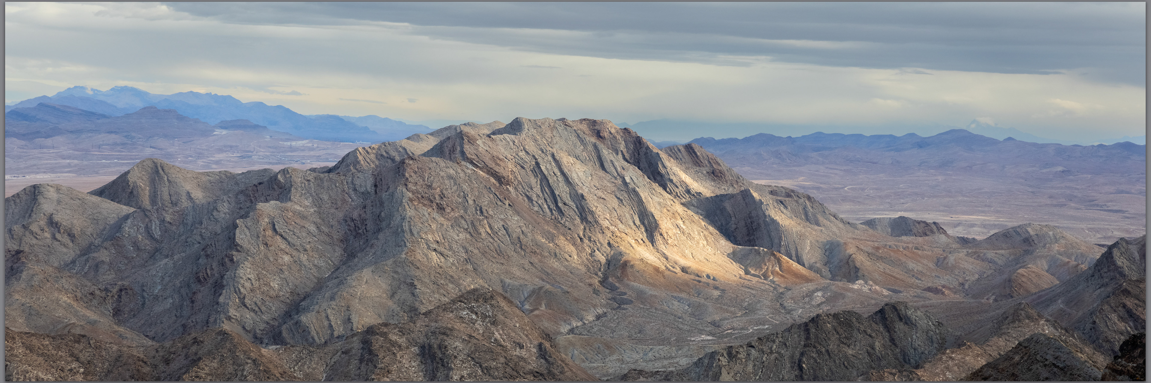 The skyward tilt of the limestone rocks of Sunrise Mountain guarding the northern end of the Frenchman Range, Mojave Desert, USA