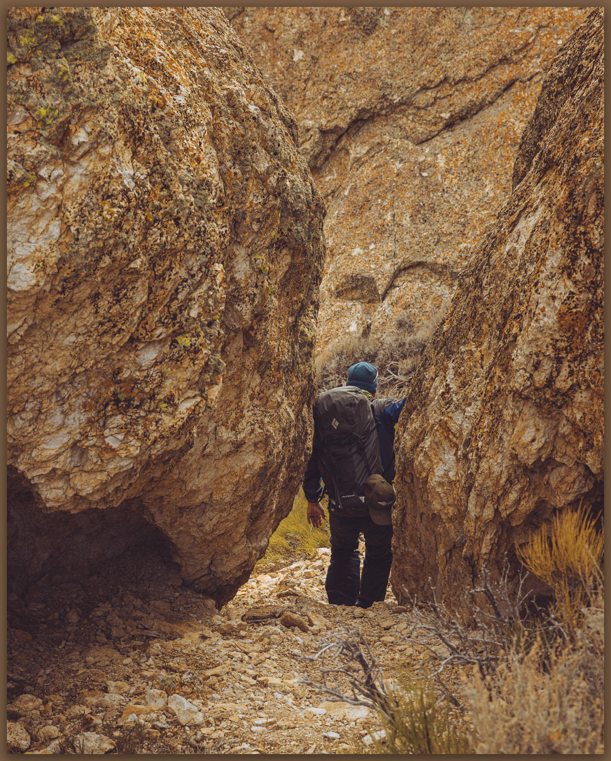 Navigation. Darren finds his way between summit boulders, Bullfrog Hills, NV, Mojave Desert, NV, USA