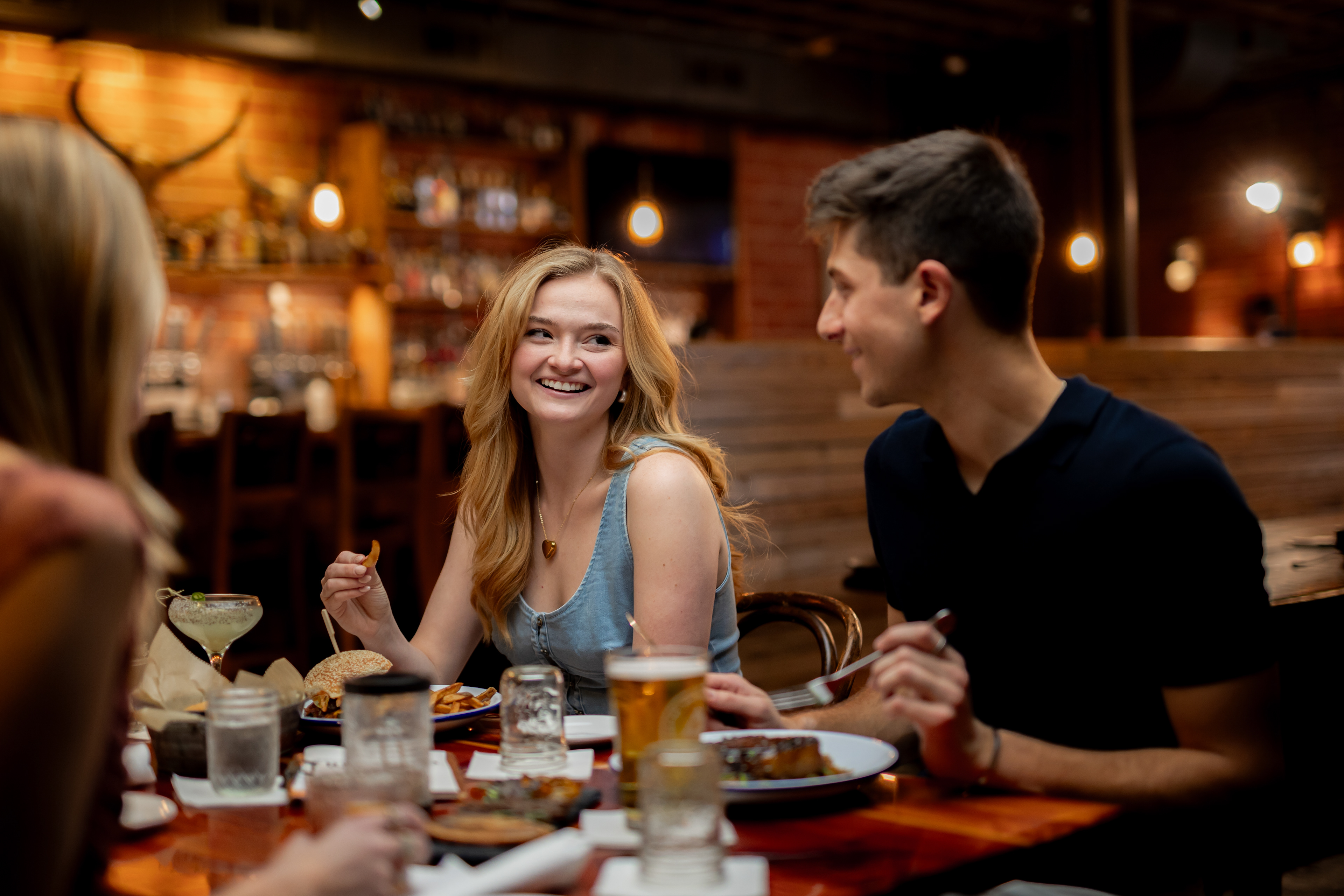 A couple on a double date, smiling at each other while eating at the Hound in Auburn Alabama