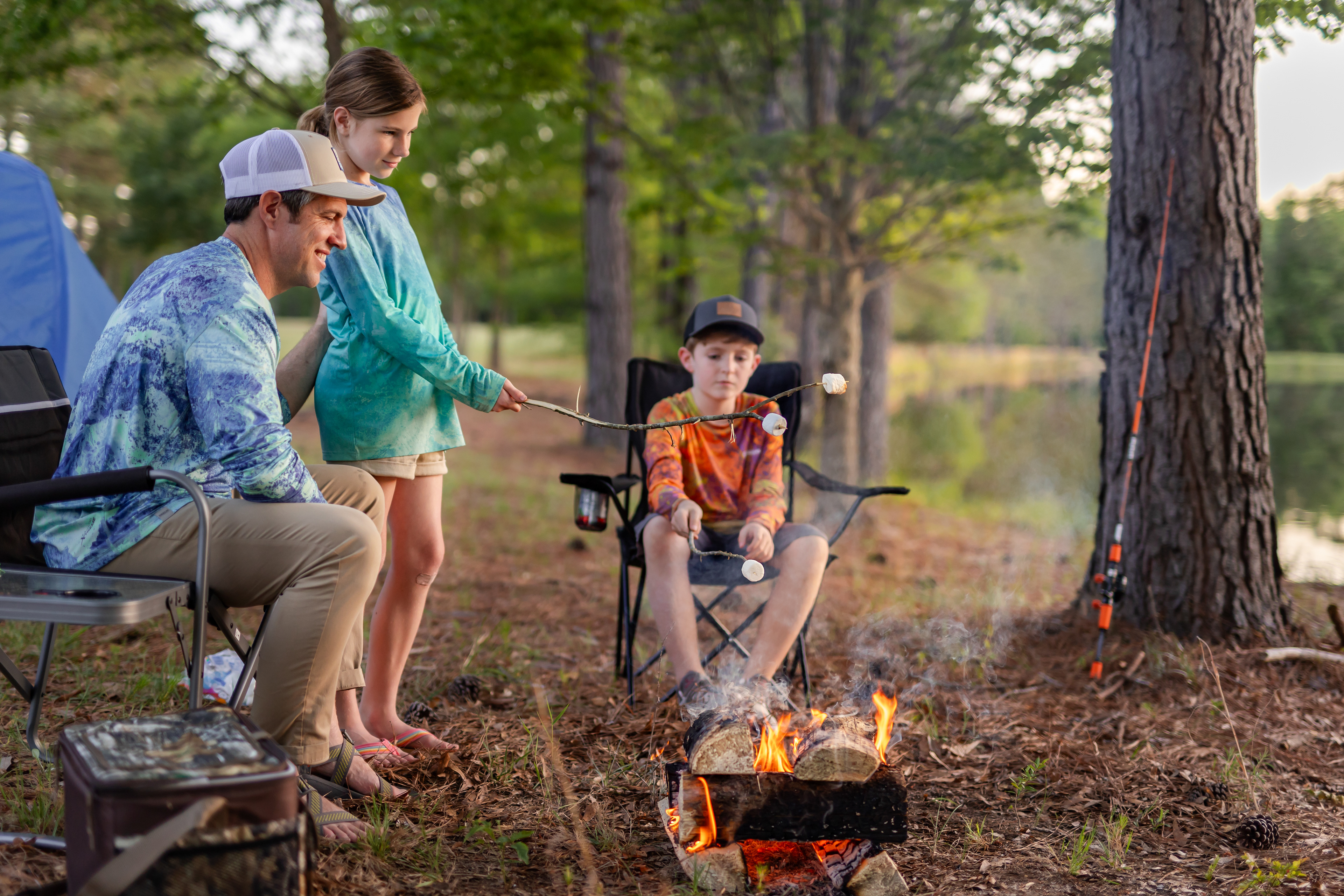 A family wearing Realtree fishing shirts roasting marshmallows over a campfire