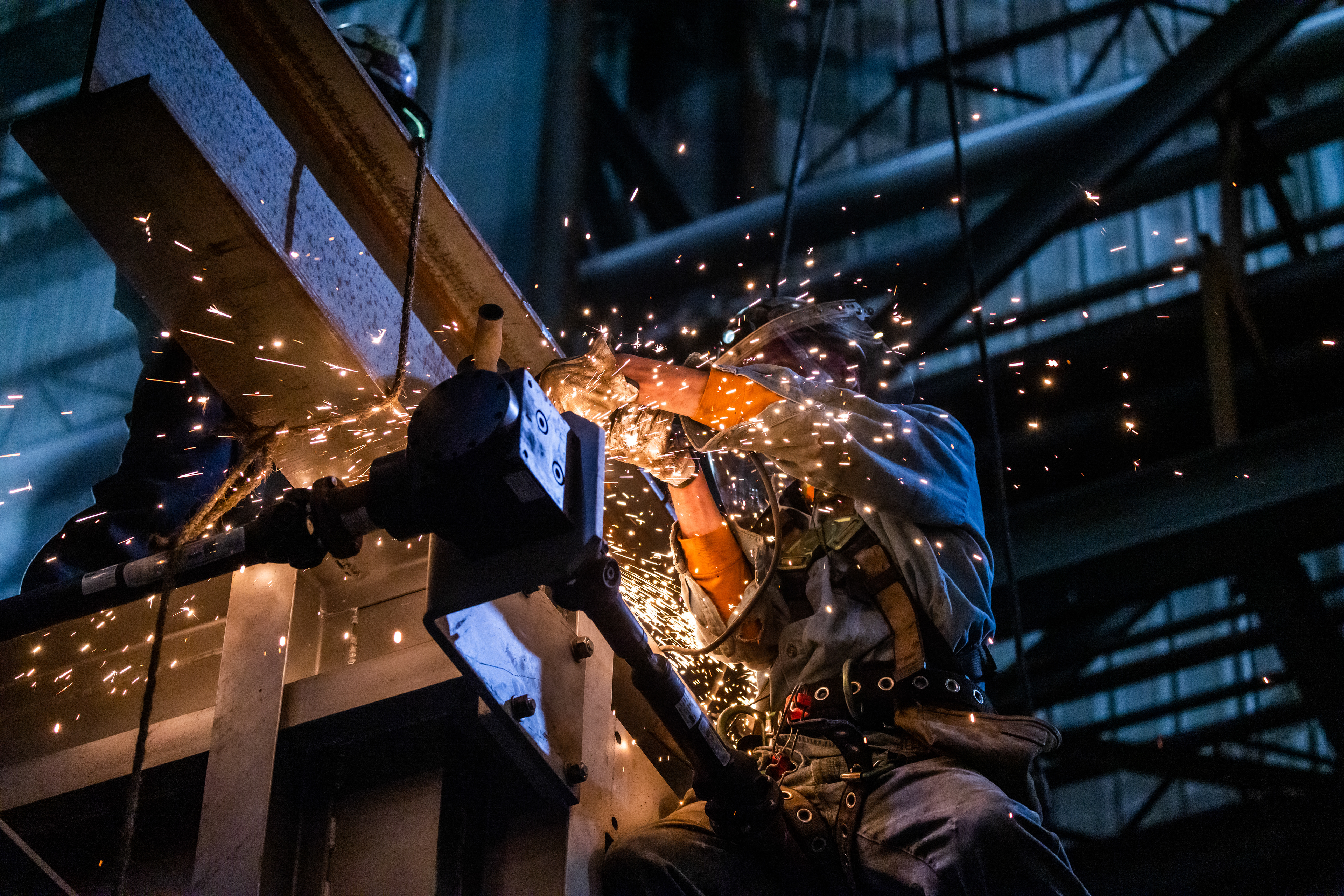 welder at night, welding steel beams with sparks flying