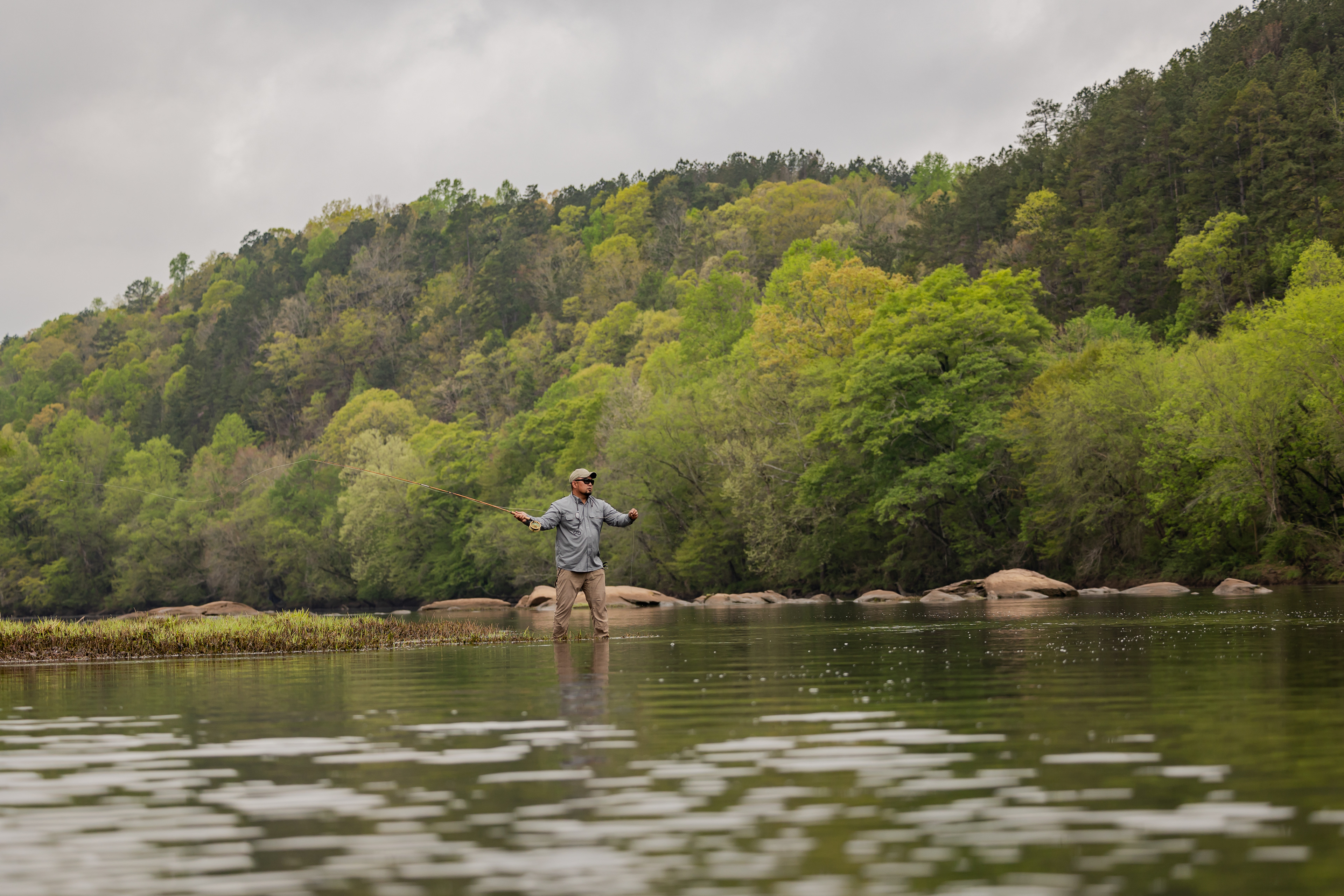 A wide picture on the Tallapoosa river, with fly fishing angler Rowell Guevarra, wearing a Realtree fishing shirt and a Realtree fishing hat