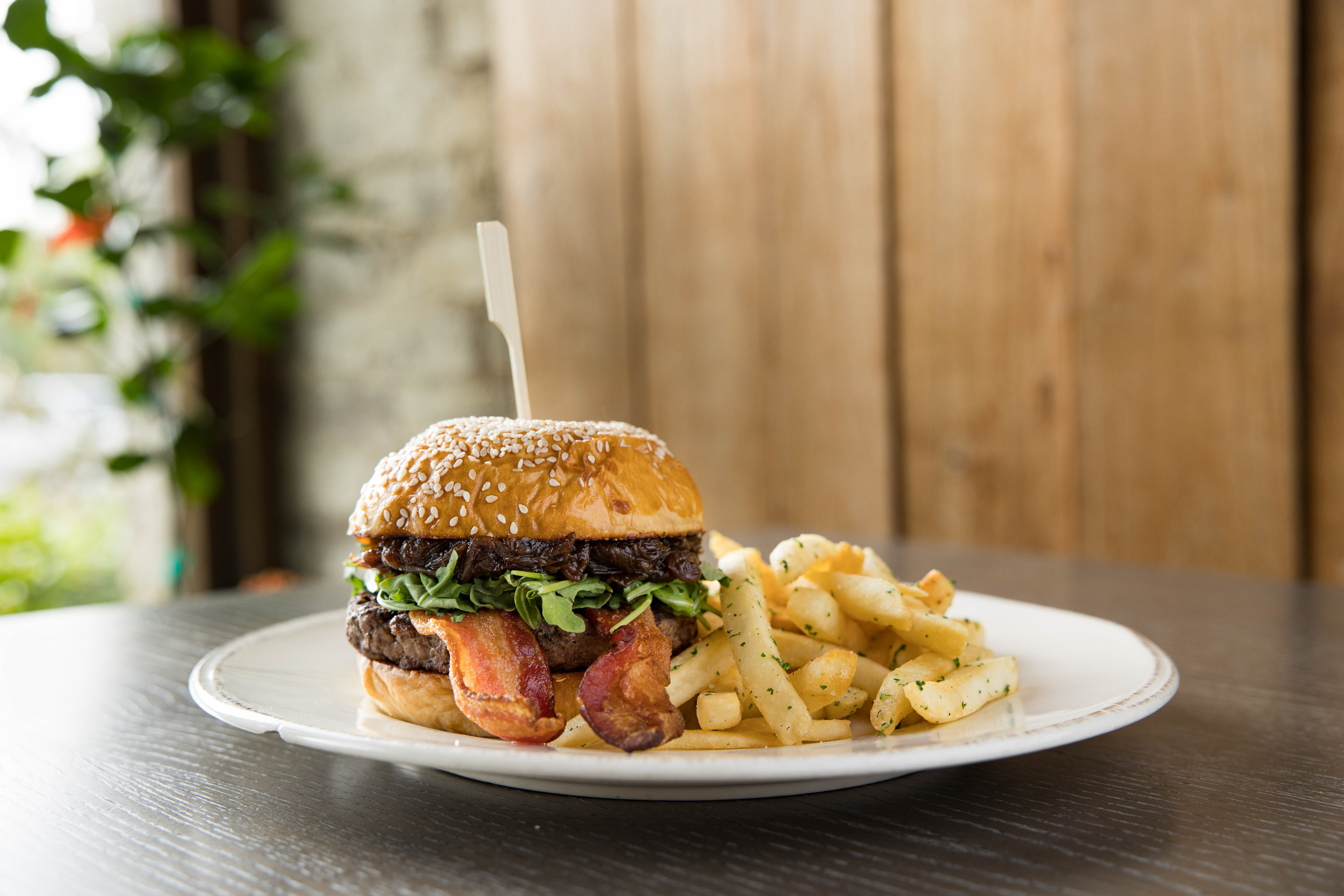 A burger with onion jam and bacon with a side of fries from Acre in Auburn Alabama