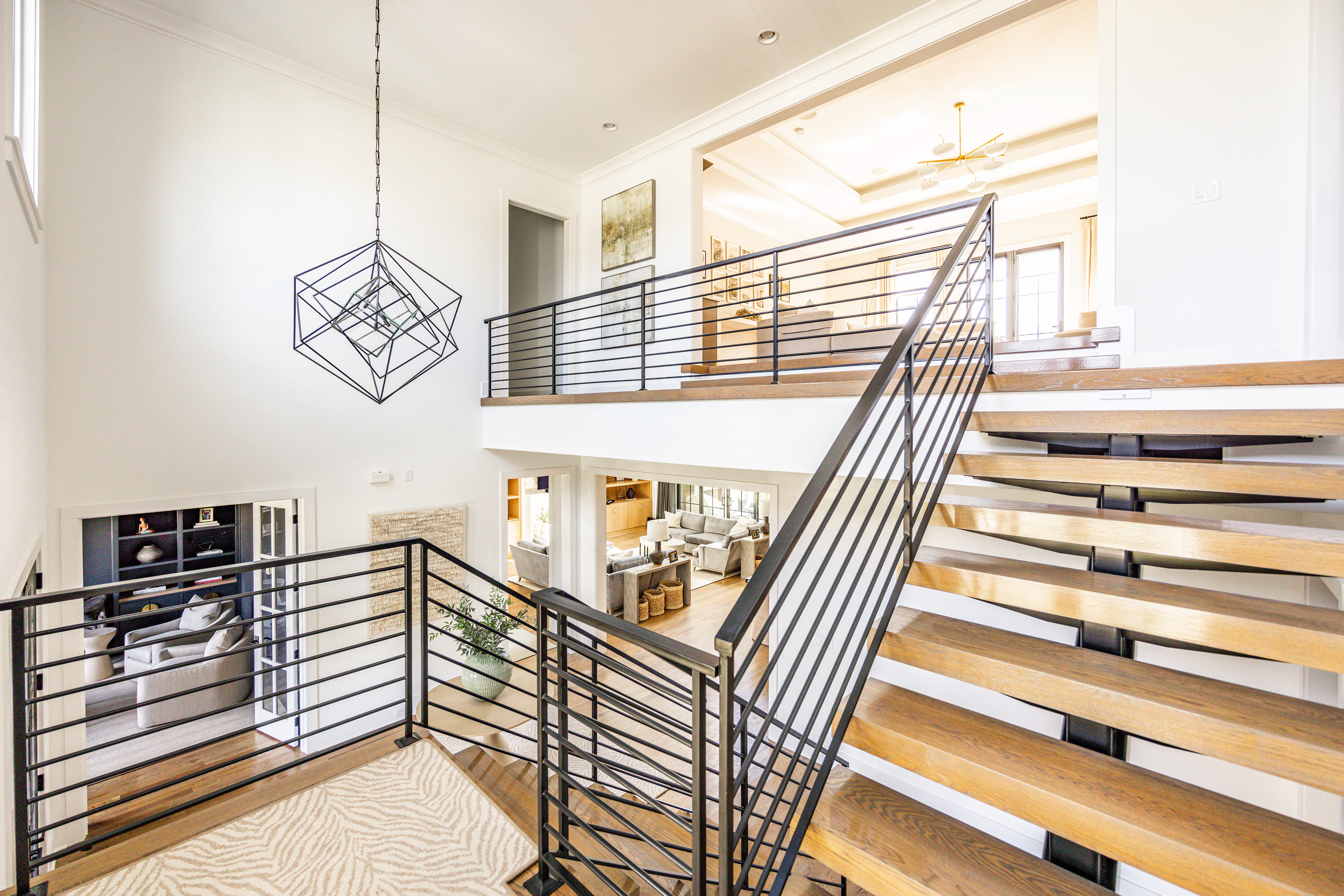 wide view of an entryway with stairs that goes into an upstairs living room, shows the flow of rooms.
