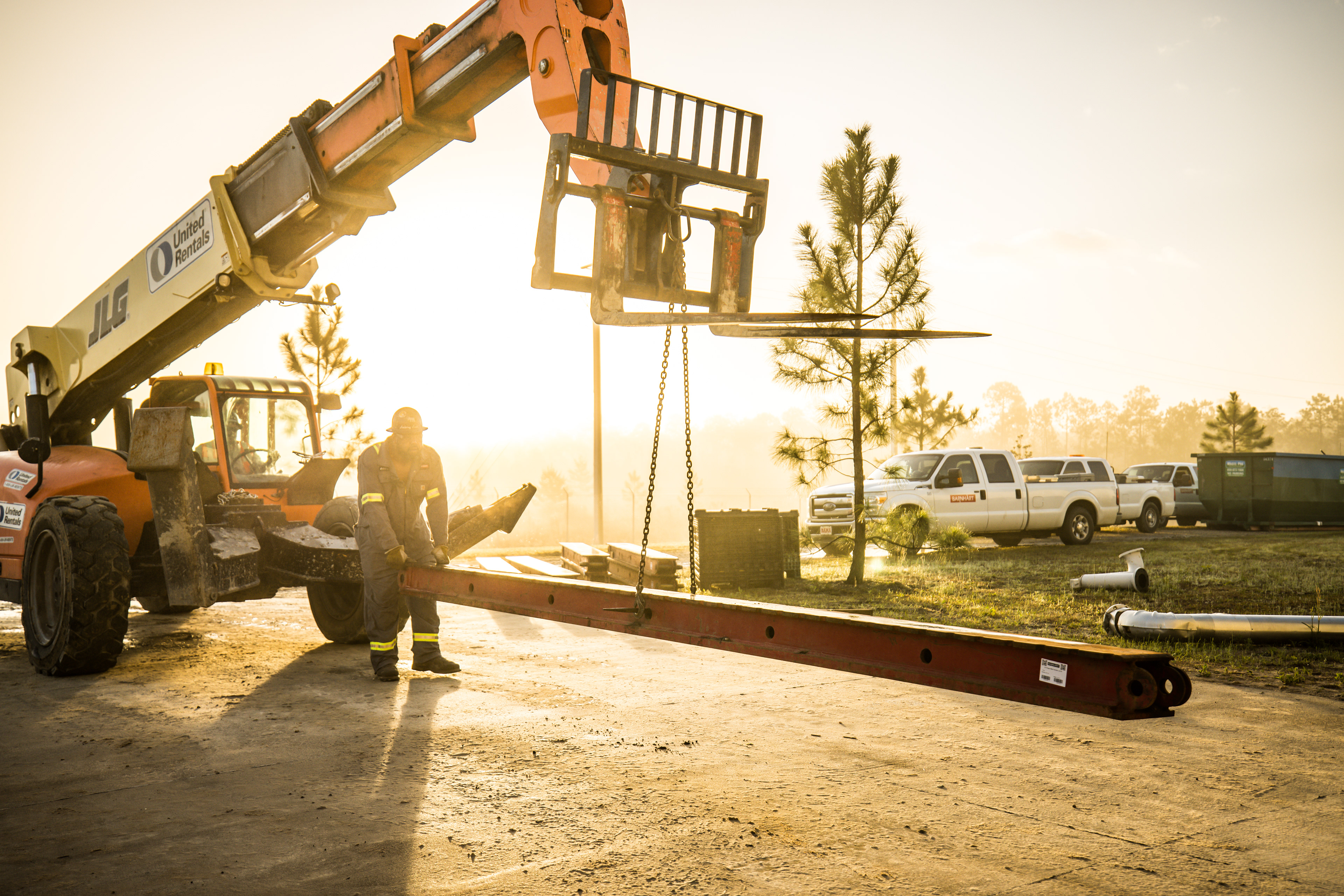 two Barnhart construction workers lift a beam with a forklift
