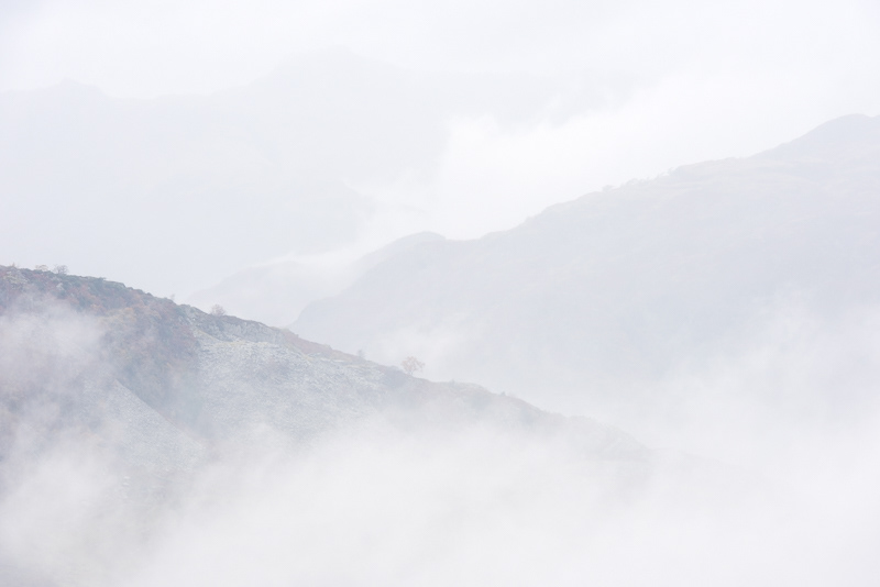 Interlinking fells in misty conditions as low cloud passes through viewed from Holme Fell in the Lake District.