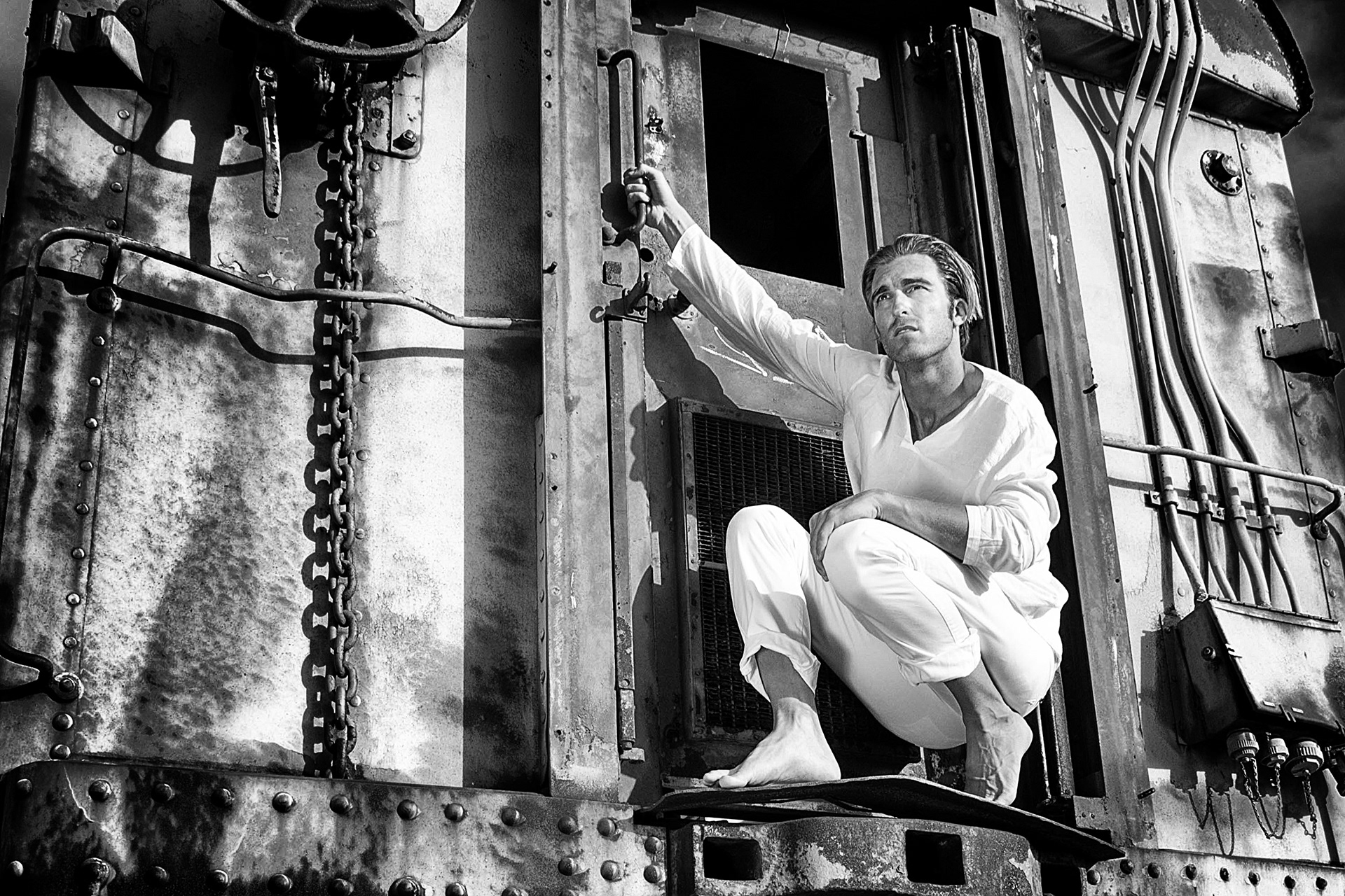 Black and white image of model, seating on the adge of the train. Picture takenby Monika Zdziebkowska