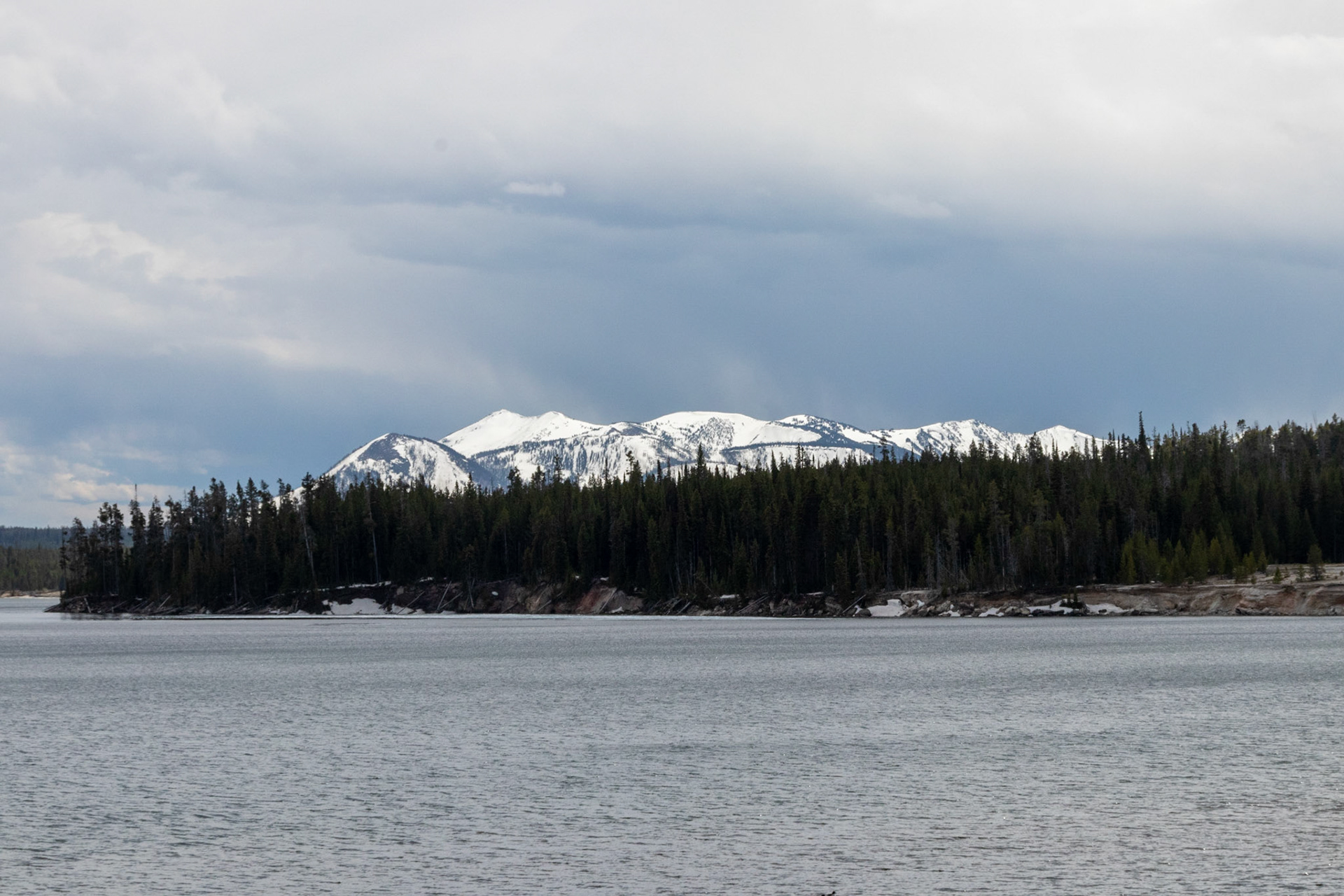 Snow capped mountains in the distance behind West Thumb Lake
