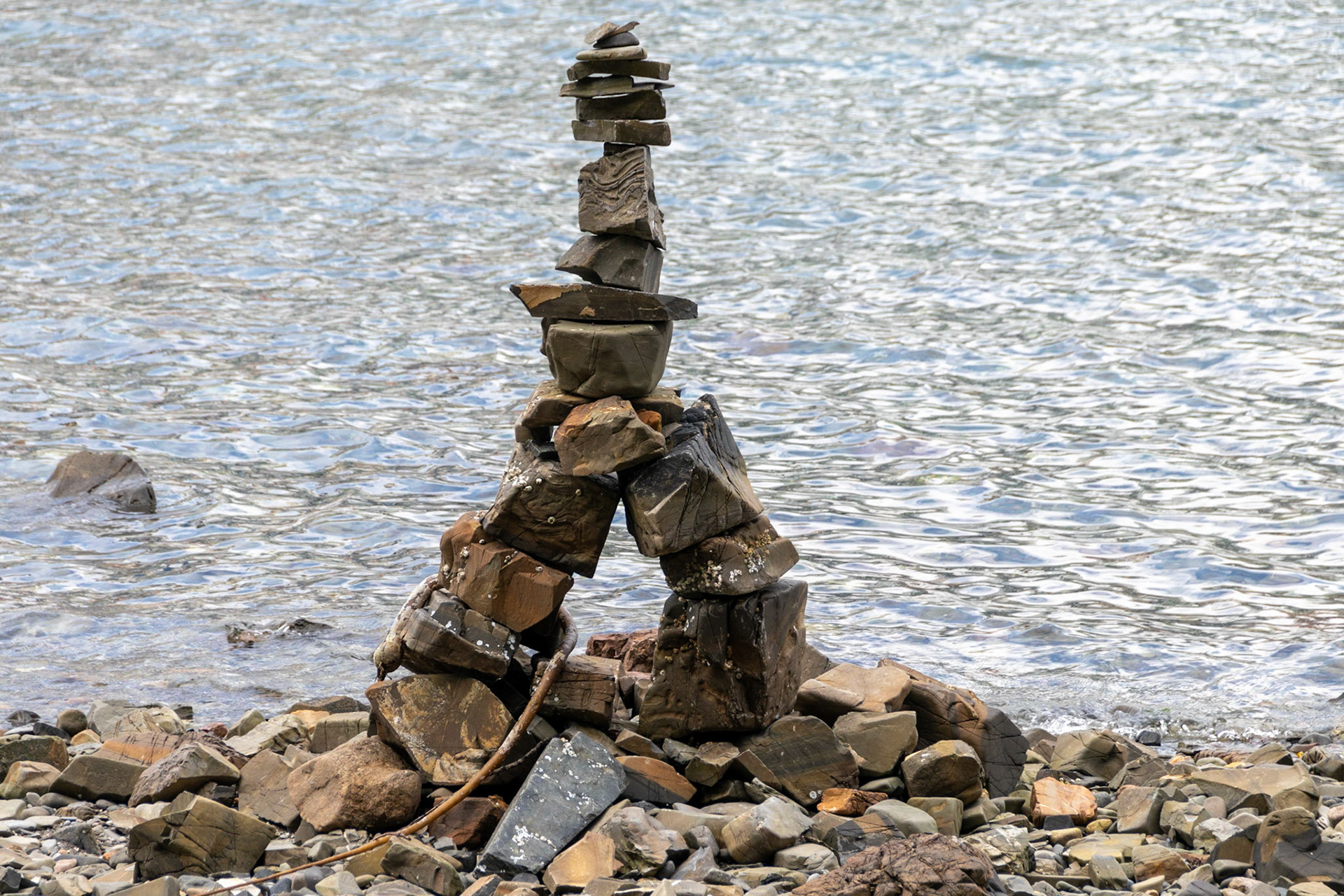 a structure of rough stones stacked in the form of a human figure, traditionally used by Inuit people as a landmark or a commemorative sign. This beach had many such structures, not all of which understood the "human form" portion as they were constructed by tourists.