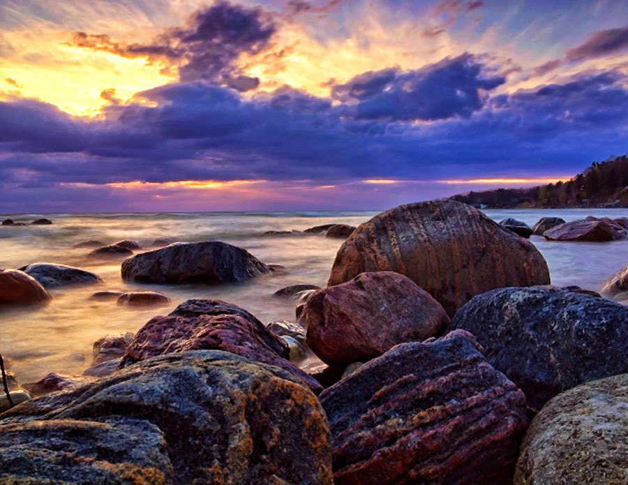 A spectacular sunset over pink rocks and flowing water on Woodland Beach in Ontario.