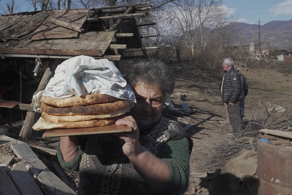 Local resident Zina Fatyan carries freshly baked bread in the village of Taghavard in the region of Nagorno-Karabakh, January 15, 2021. Following the military conflict over Nagorno-Karabakh and a further signing of a ceasefire deal, the village was divided into two parts: the Azeri forces stayed in the upper western end and those ethnic Armenians who did not flee live now in the east, reinforced by armed units. Picture taken January 15, 2021. REUTERS/Artem Mikryukov