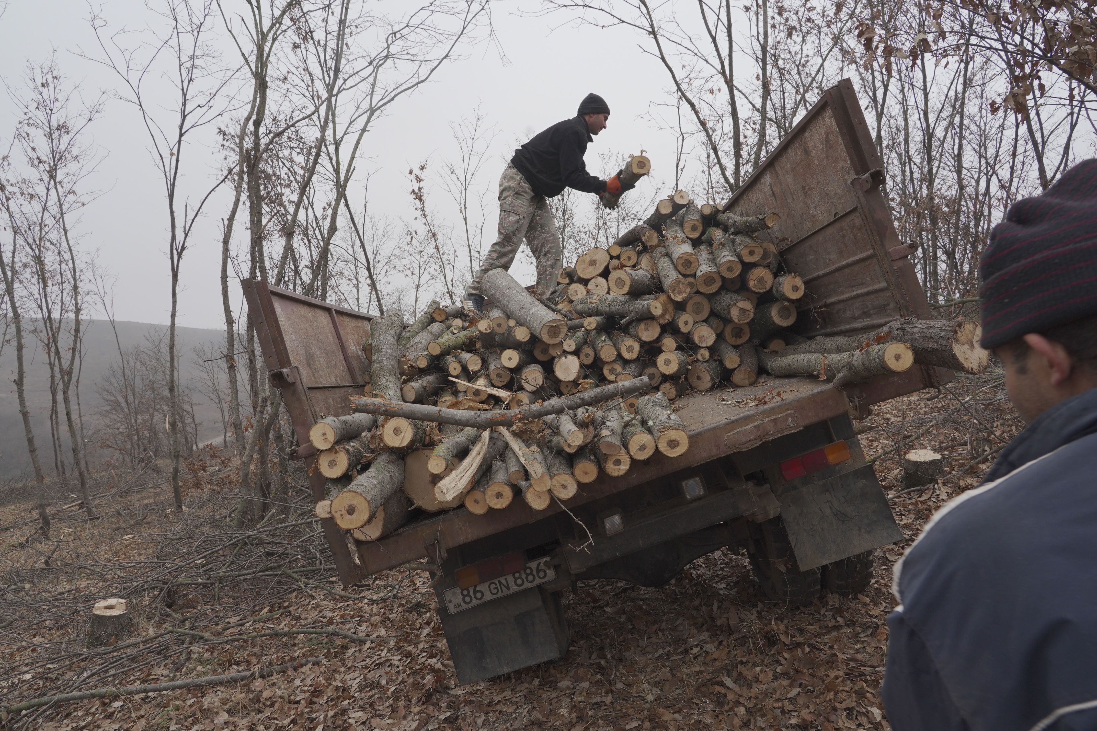 A local resident puts logs cut for firewood in the back of a truck near the village of Taghavard in the region of Nagorno-Karabakh, January 12, 2021. Following the military conflict over Nagorno-Karabakh and a further signing of a ceasefire deal, the village was divided into two parts: the Azeri forces stayed in the upper western end and those ethnic Armenians who did not flee live now in the east, reinforced by armed units. Picture taken January 12, 2021. REUTERS/Artem Mikryukov