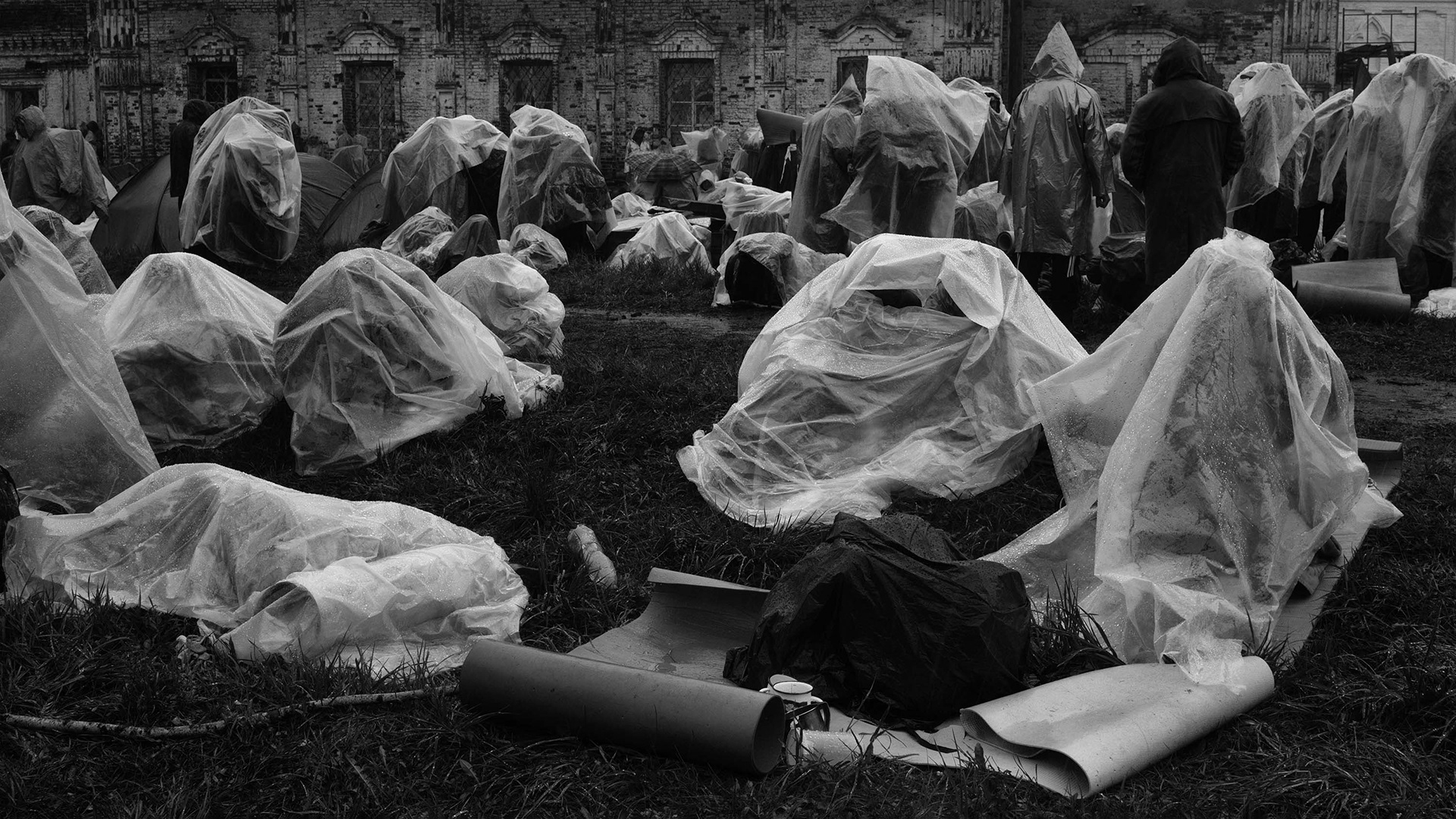 Pilgrims rest taking shelter from the rain with plastic sheet