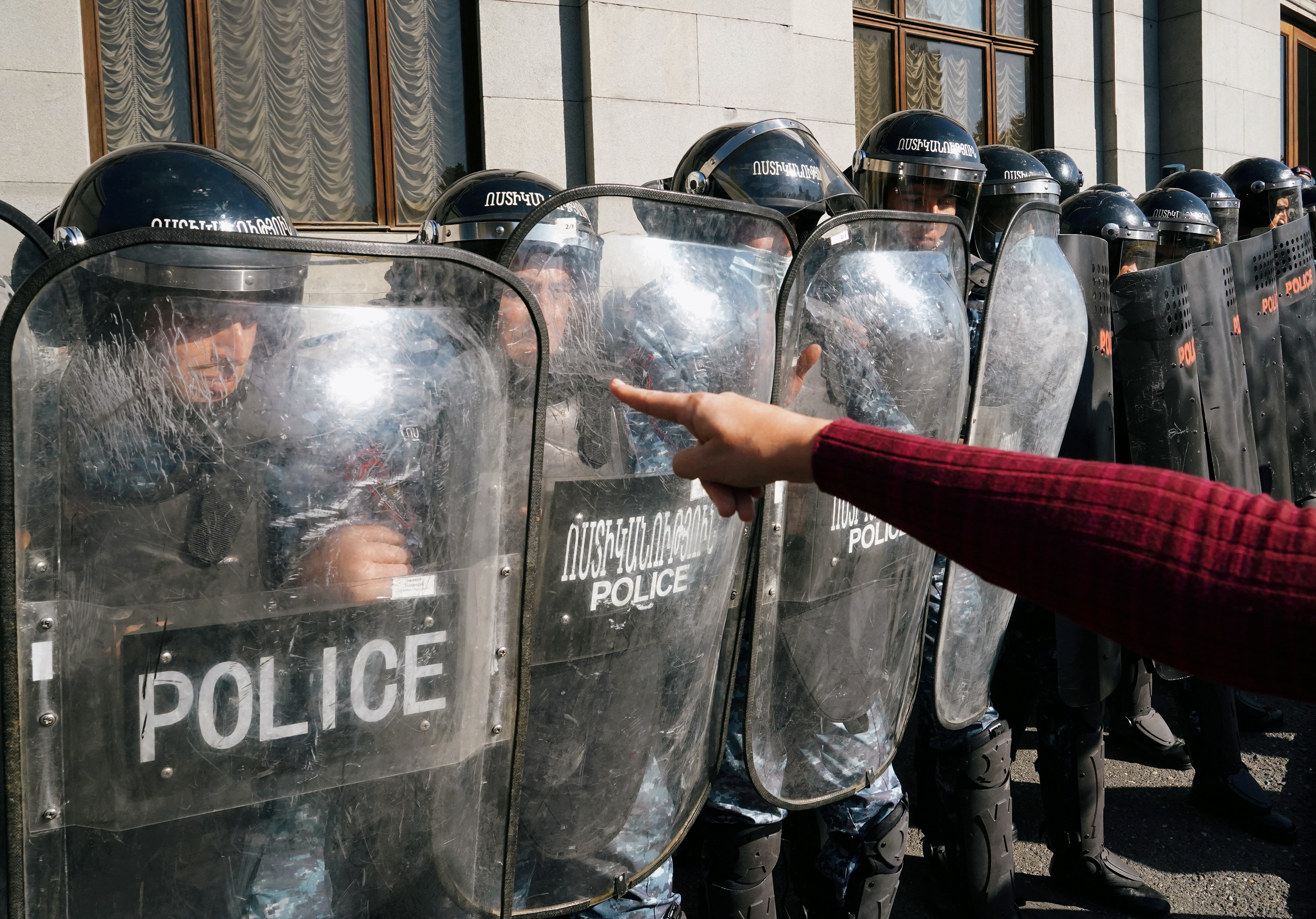 A demonstrator gestures towards law enforcement officers standing guard during an opposition rally to demand the resignation of Armenian Prime Minister Nikol Pashinyan following the signing of a deal to end the military conflict over the Nagorno-Karabakh region, in Yerevan, Armenia November 11, 2020. REUTERS/Artem Mikryukov