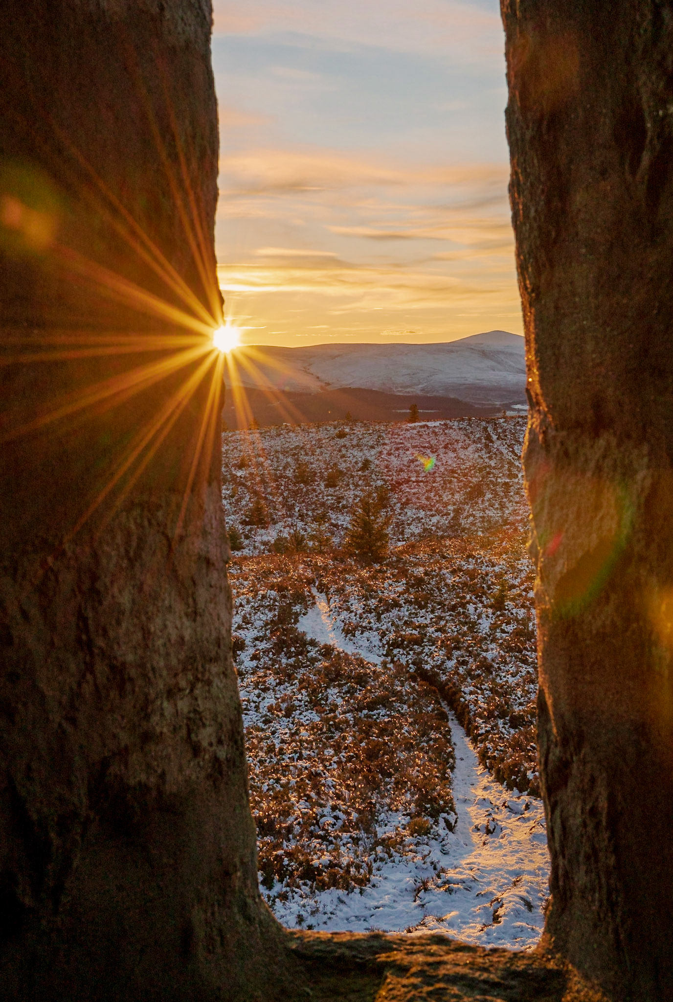 Image of mountains covered in snow at sunset, photo taken through a window inside an old tower at the top of the hill at Scolty Hill near Banchory in Aberdeen