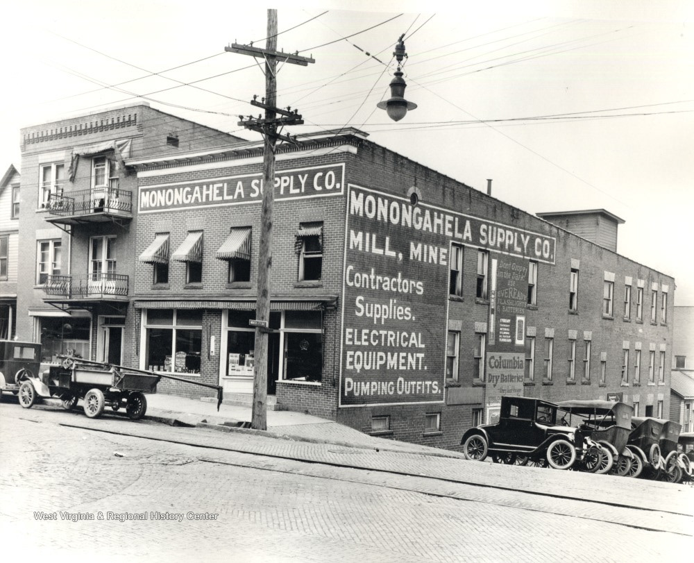 A photo of the Monongahela Supply Co. in the 1920s, courtesy of West Virginia Regional History Center. Station wagons line the building, which advertises "Mill, Mine, Contractor Supplies, Electrical Equipment, Pumping Outfits".