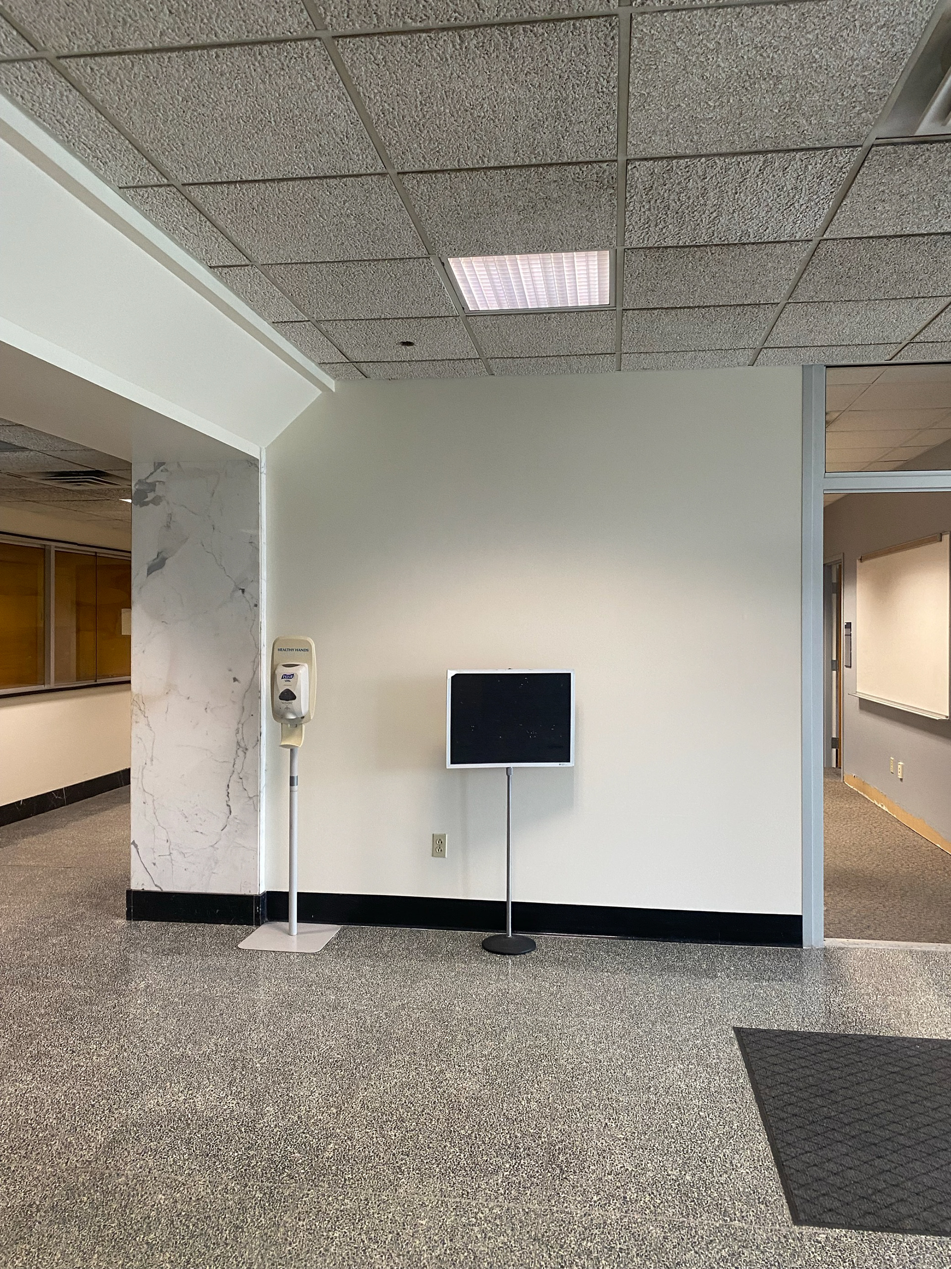 The right side of the main floor in Engineering Sciences Building, a plain white wall with one white marble slab.
