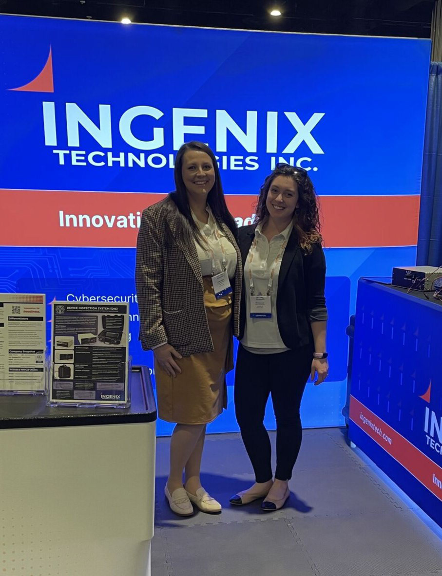 Ingenix CEO Nadia Wright and Director of Business Development, Mallory Lind, posing in front of the backlit Ingenix Technologies backdrop during a conference. 