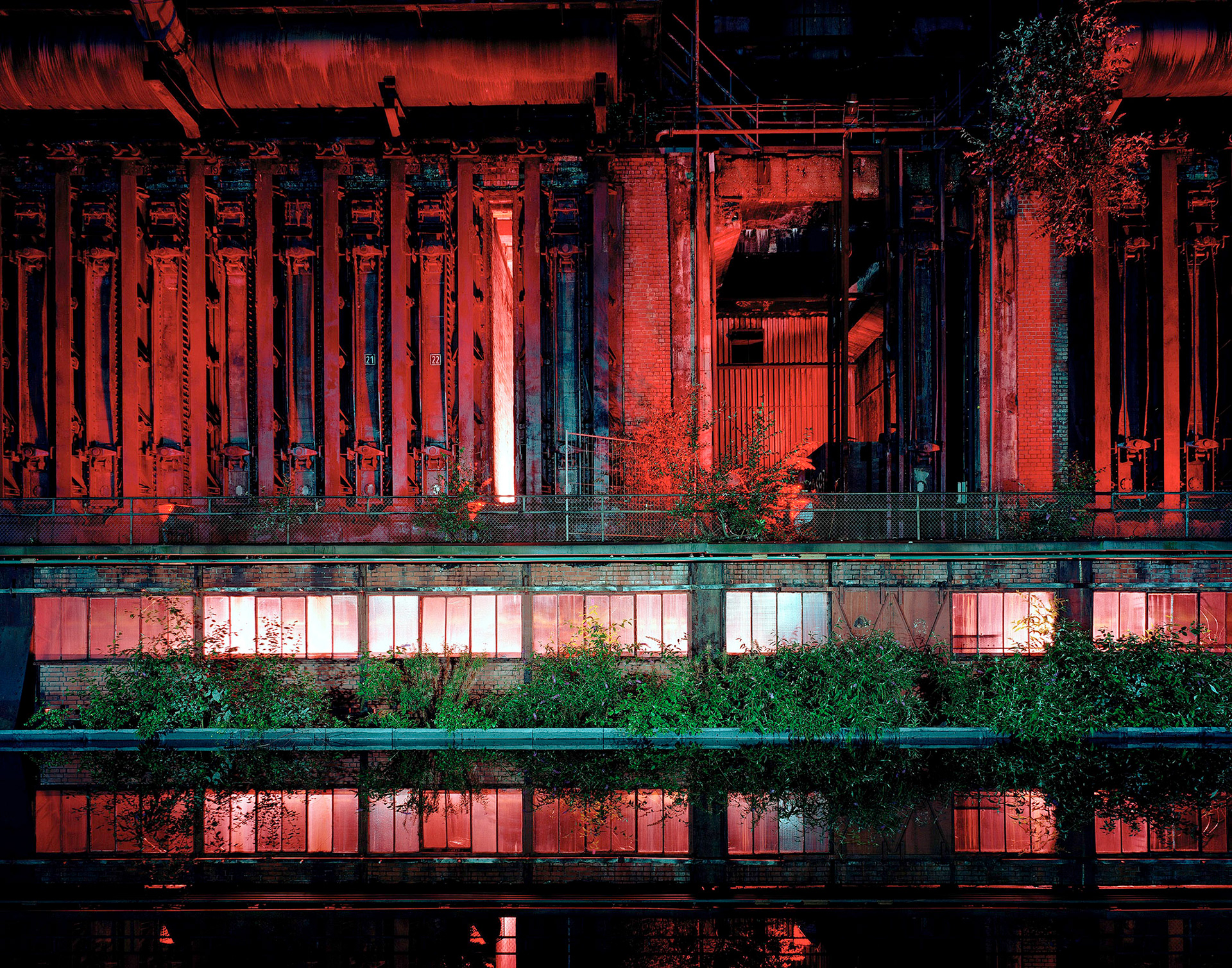 „Nachtaufnahme einer Industrieanlage in Essen im Ruhrgebiet, modern beleuchtet mit warmem Licht und klaren geometrischen Strukturen.“