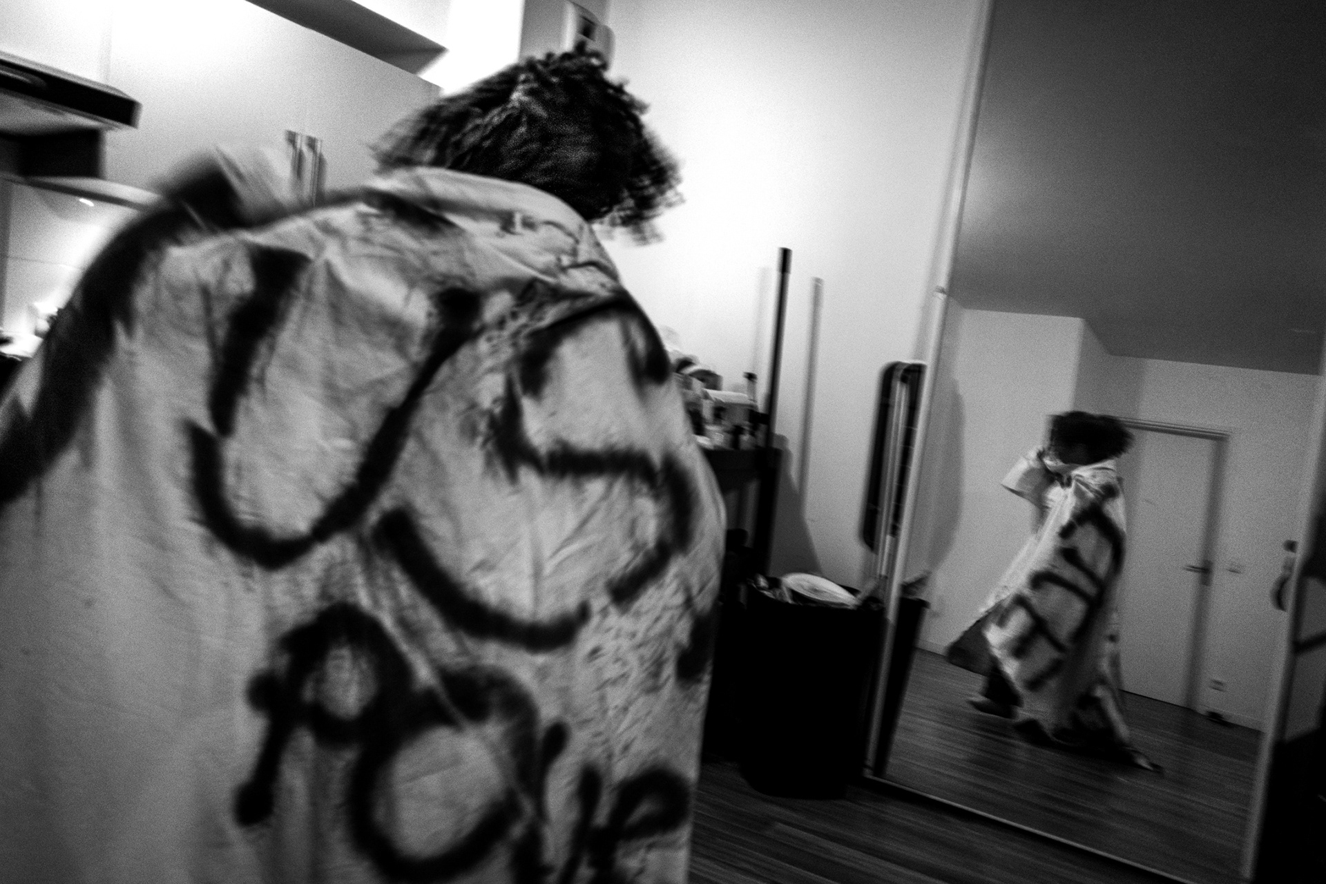 Rose Oyemi’s home in Aubervilliers, Paris. February 11, 2026. Kael, a member of the BlakoutGeneration, wraps herself in the banner created for the open mic event at the Belleville belvedere. The open mic is in tribute to El Hacen Diarra, who died in police custody following a violent arrest by the police on the night of 15–16 January 2026.