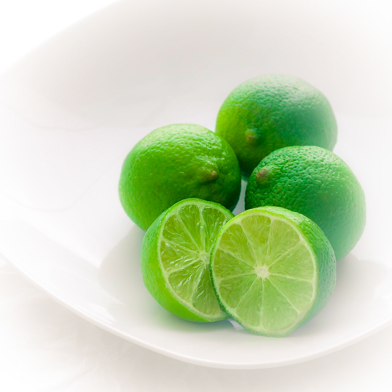 Just a simple shot of green limes on a white plate and white background for an online recipes effort.