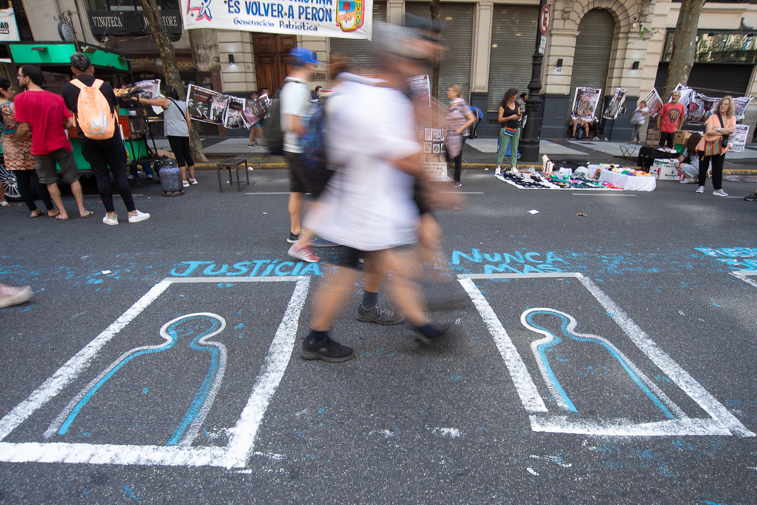 Transeúntes caminan entre las intervenciones realizadas en el asfalto de la Avenida de Mayo en el Día Nacional de la Memoria por la Verdad y la Justicia en la Ciudad Autónoma de Buenos Aires, Argentina, el 24 de Marzo de 2023.