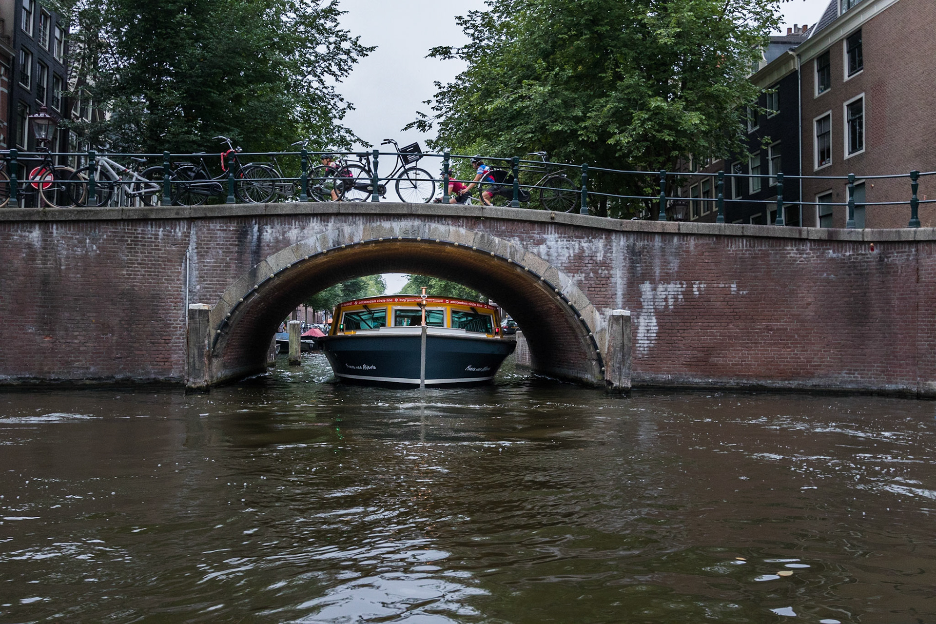Sightseeing boat squeezing through arch in Amsterdam Canal, Netherlands (2018)