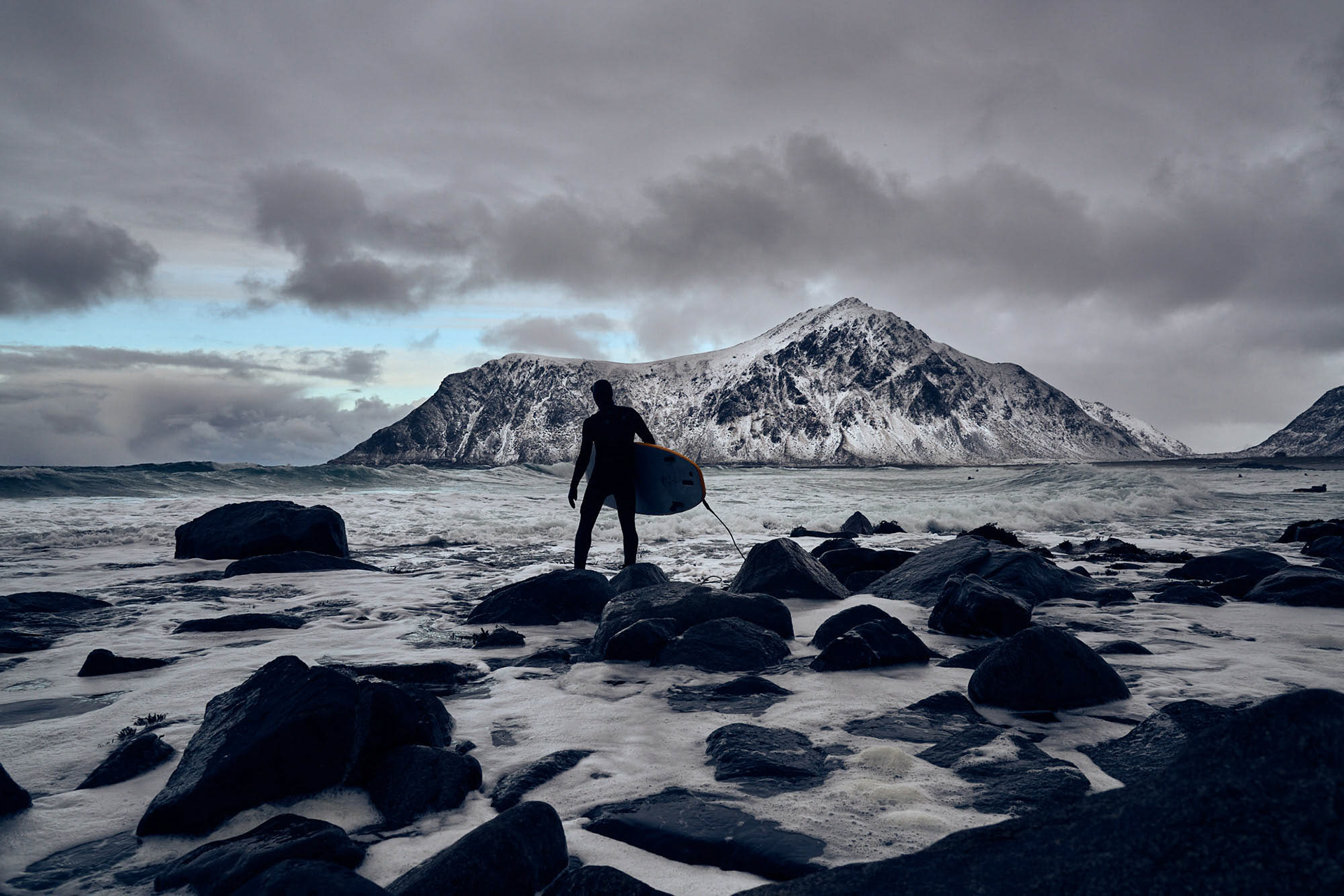 A lonely surfer ready to dive into the cold waters of Norway