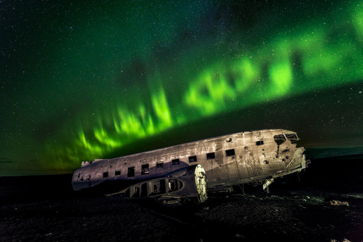 Northern lights over famous airplane wreck in Vik beach, Iceland.