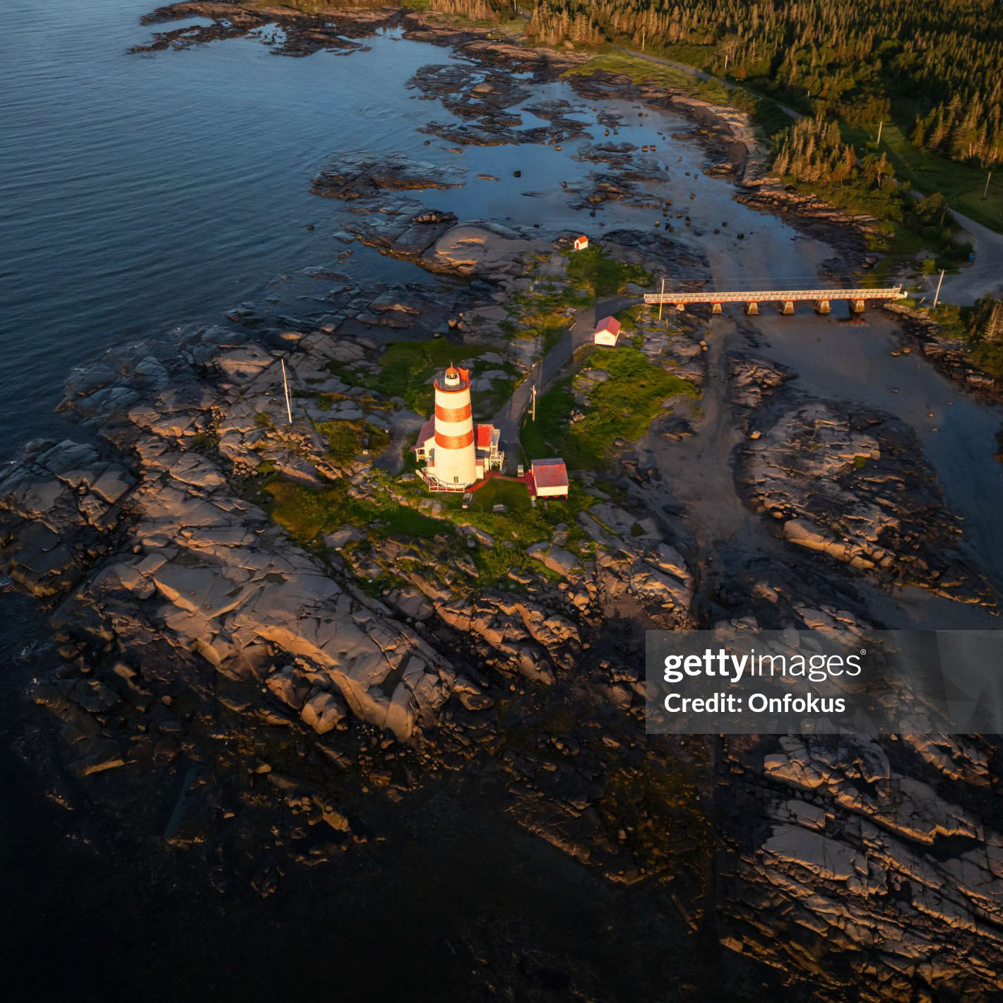 Aerial view of Pointe-des-Monts Lighthouse at sunrise, Cote-Nord, Quebec. The sun is rising over the St. Lawrence river on this day of summer in Cote-Nord, Quebec, Canada.
