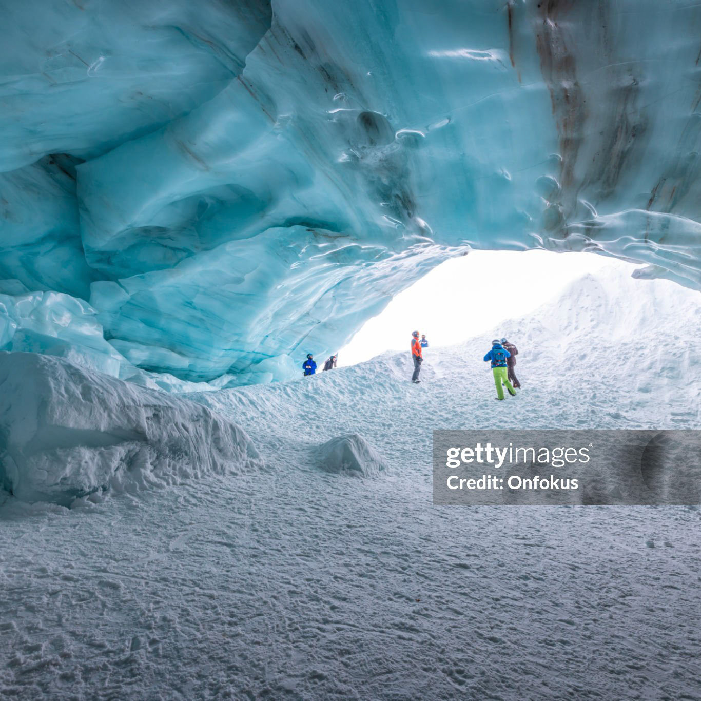 Whistler, British Columbia, Canada - February 8 2022 : Skiers and snowboarders standing at the entrance and inside of an ice cave in Whistler, BC. This is the Blackcomb Glacier Cave.