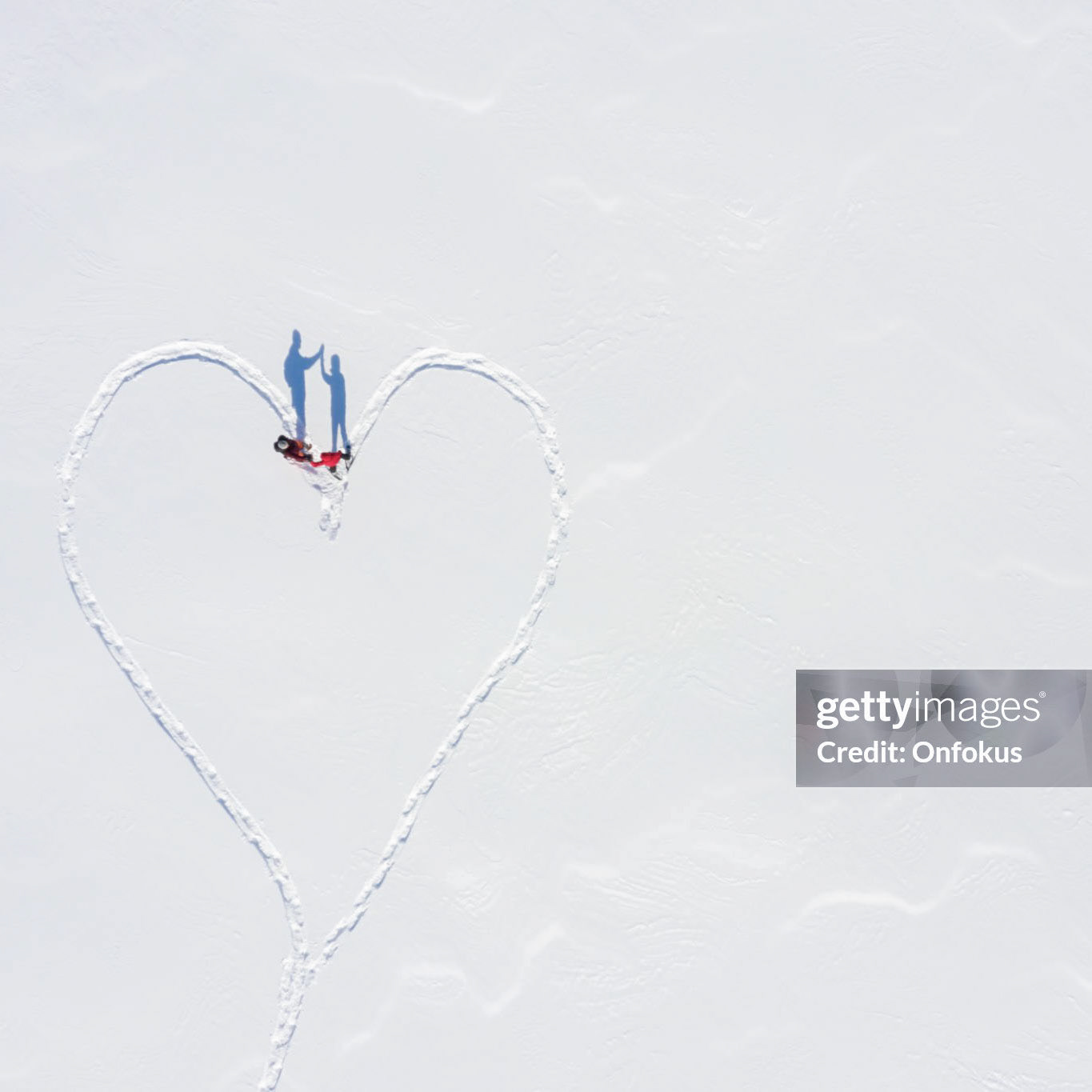 Aerial View of a Couple Snowshoeing Outdoor in winter, they are doing a heart shape with the footprint  while walking in the fresh powder snow.