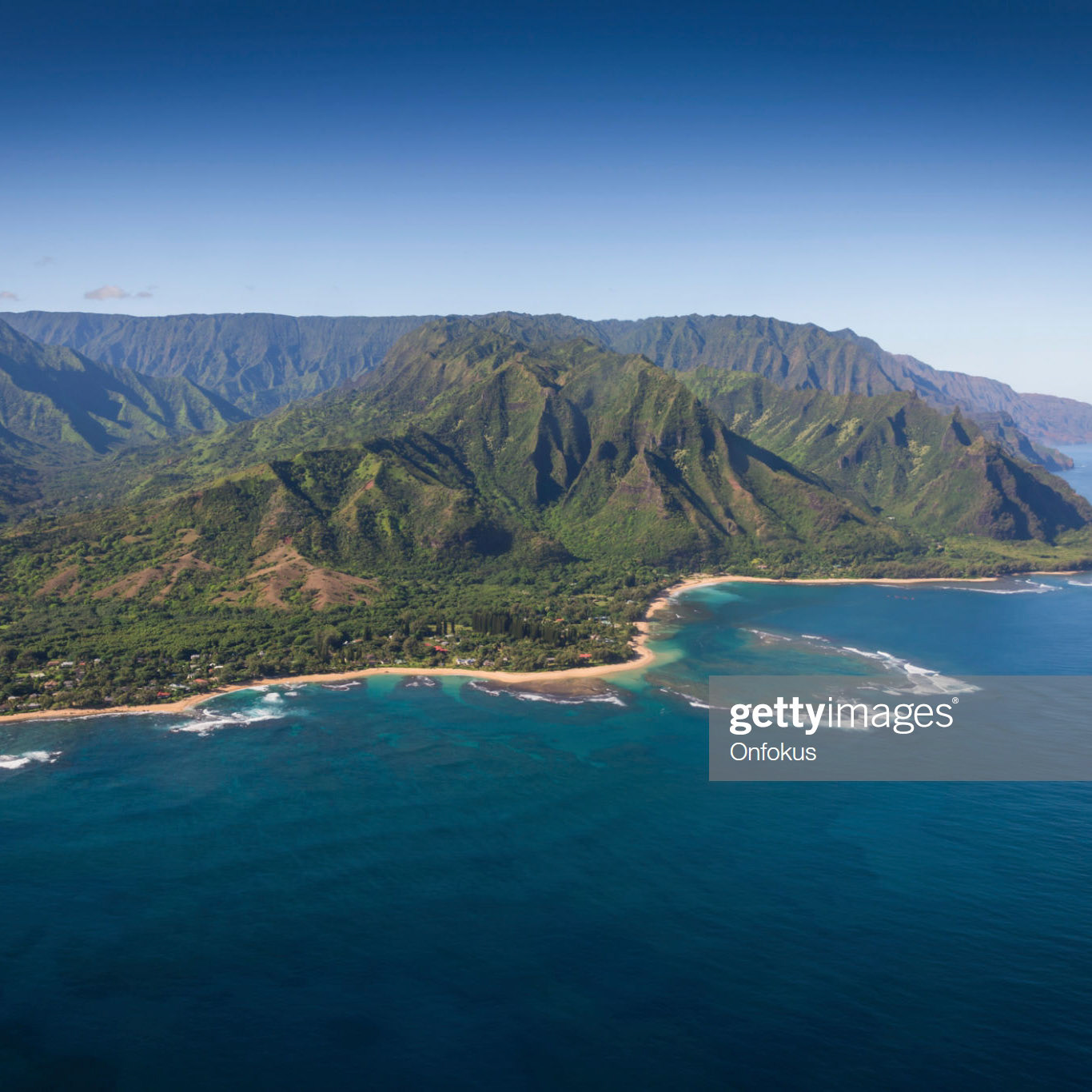 Aerial View of Na Pali Coast, Kauai, Hawaii. The picture was taken during the summer in day time. The crystal blue ocean is surrounding the volcanic mountain chain. Several touristic cruise boats are passing by.