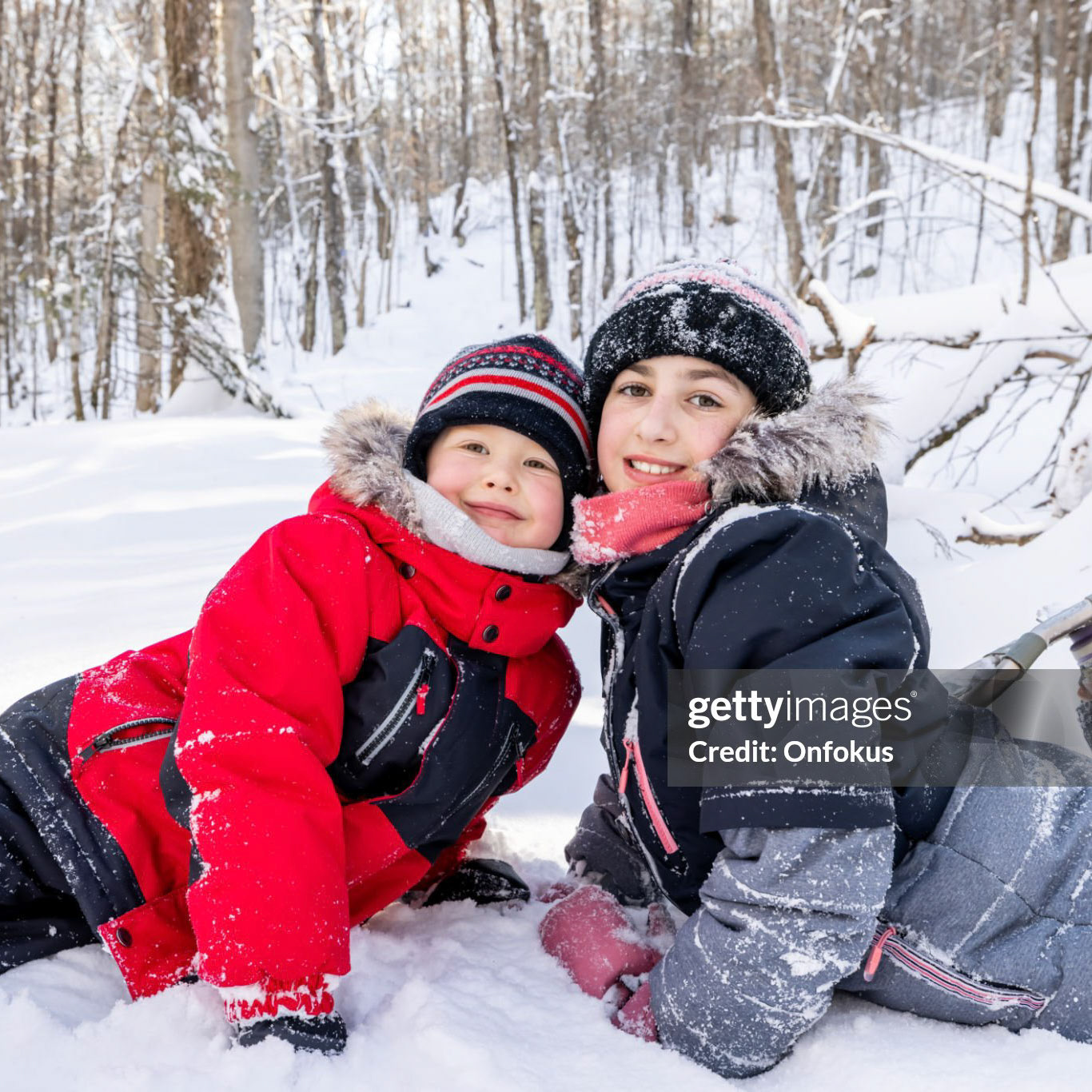 Brother and Sister Having Fun Snowshoeing Outdoors in Winter. The little boy and the little girl are taking a break during this winter sport. They are looking at the camera and smiling. It is a beautiful sunny winter day.