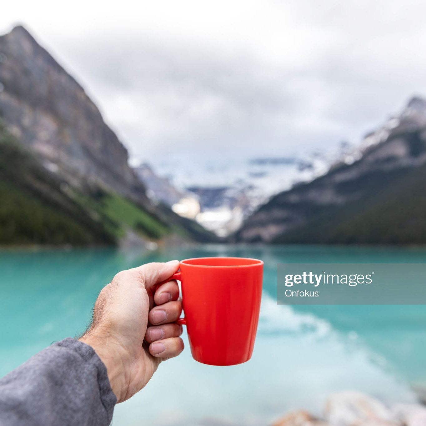 Human Hand Showing a coffee cup at Lake Louise in Banff National Park, Canada