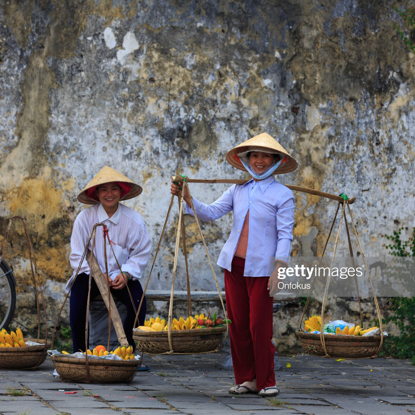 Hoi An, Vietnam - April 9, 2013: Vietnamese women holding with fruits baskets and asking tourist to take picture for money.