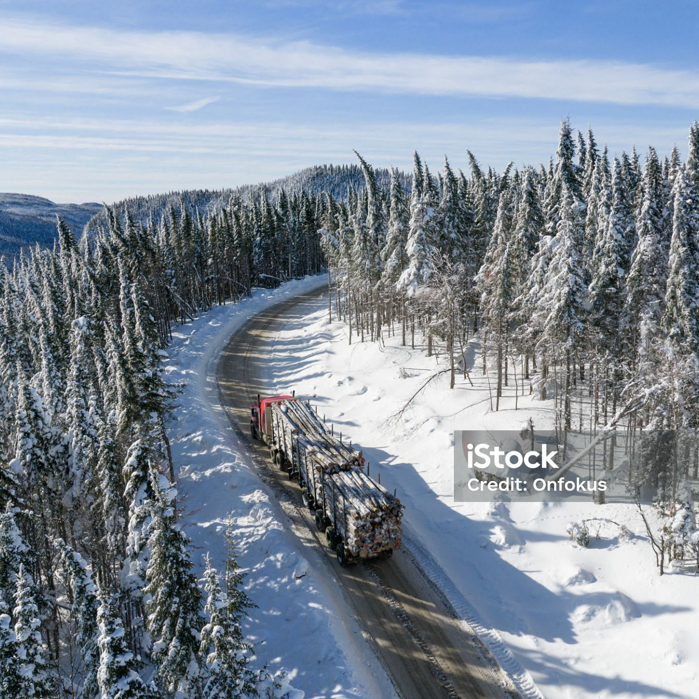 Aerial View Of Forestry Workers and Machinery During Winter, Quebec, Canada.A semi-trailer transports the timber from the cutting site to the sawmill.
