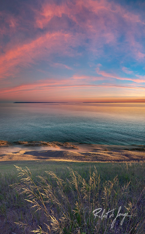 Looking North from Sleeping Bear Point at dawn with pink clouds and sunlit grasses in the foreground