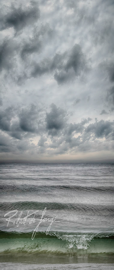 A wave breaks on the shore of Lake Michigan on a cloudy day