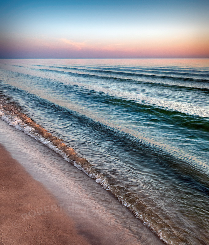 A series of waves approach the shore on Lake Michigan at sunset