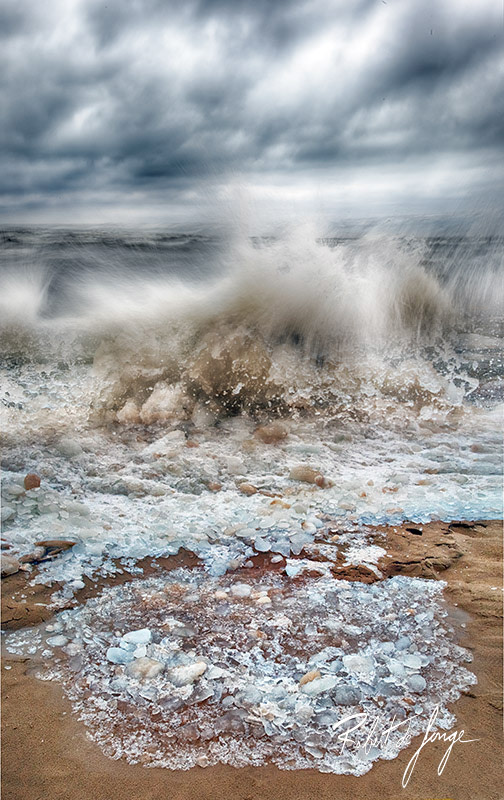 Water and ice crash the beach as warmer weather breaks up the ice along Lake Michigan