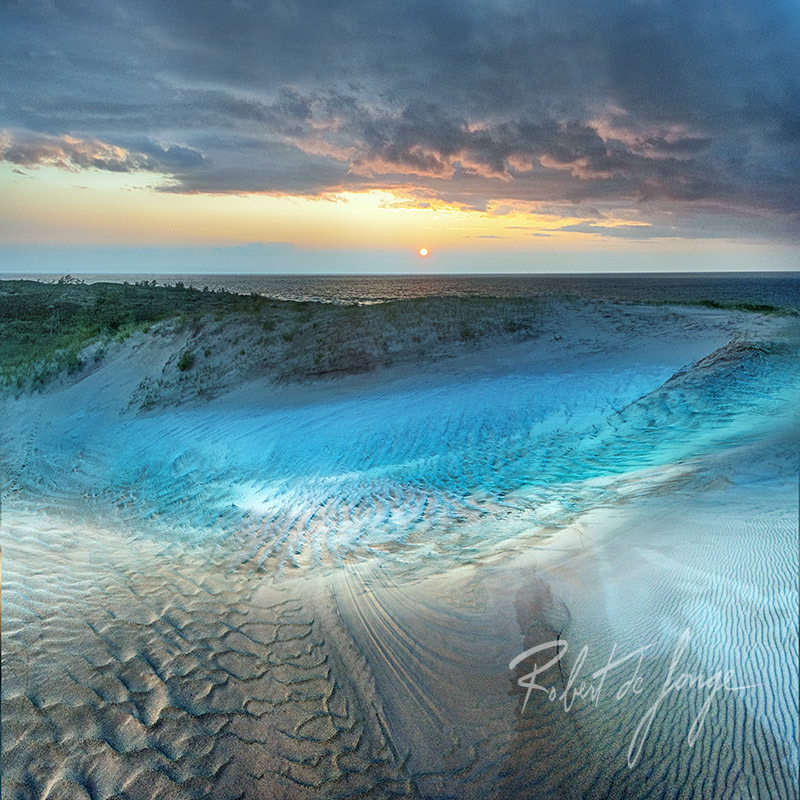The sun sets over Sleeping Bear Point and the turquoise shadows appear behind the dunes