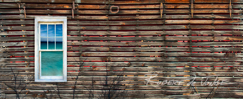 The side of a corn crib with a window from a nearby farmhouse.