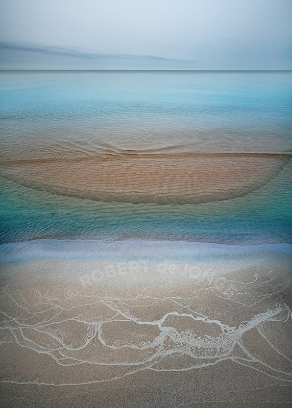 A calm hazy morning on Lake Michigan where sandbars created by recent storms create beautiful ripples in the minimal wave action