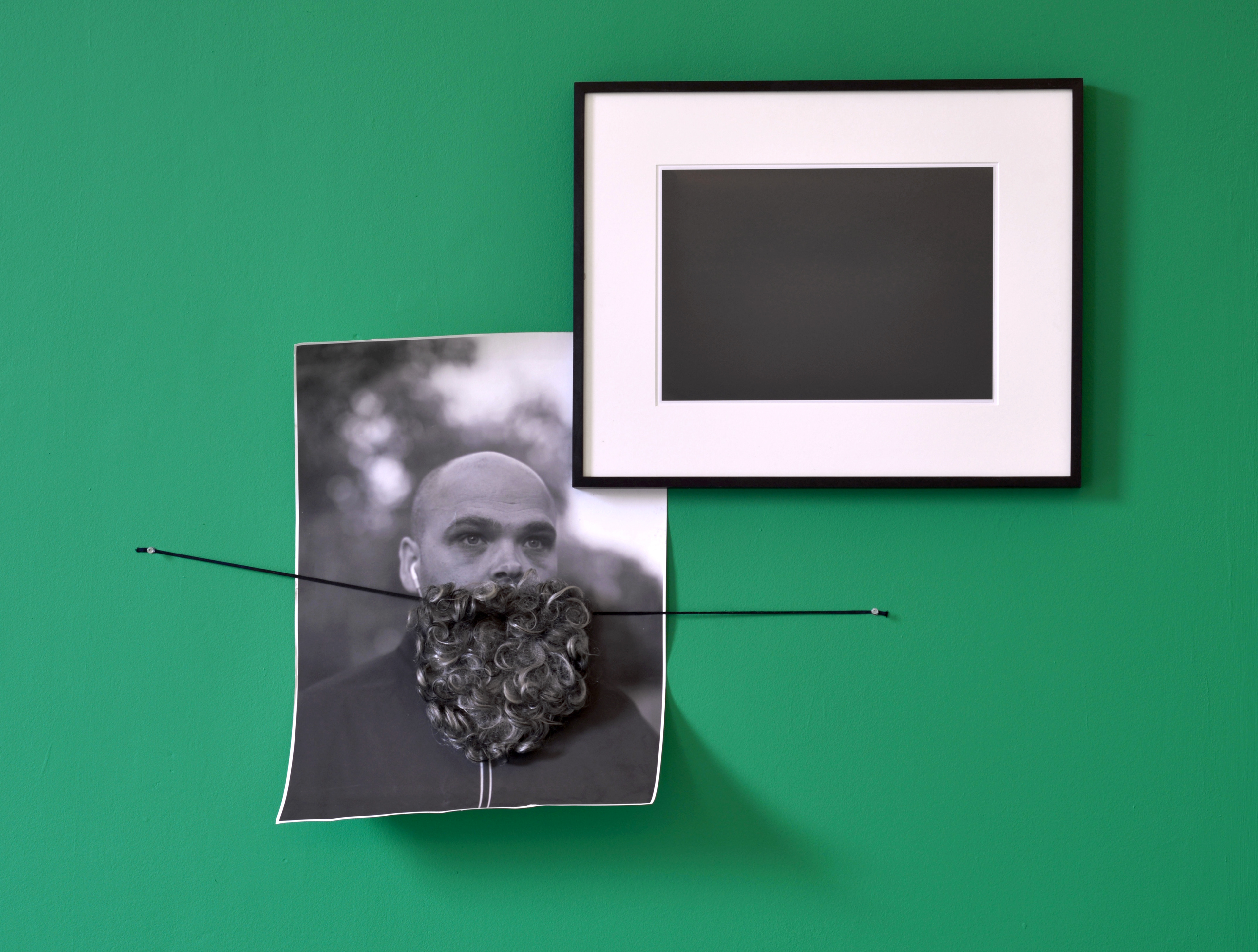 This Places Everything; The Hut Project, 2013; The Hut Project, Conceptual Beard, 2011, Black and white Inkjet print (photo-documentation of Christopher Bird's participation in Ryan Gander's We Are Constant, 2009), Digital C-type print in black wooden frame with card mount (photograph of The Hut Project Painting with Art & Language taken in the dark, as per The Hut Project, Untitled by Giorgio Sadotti, 2009, as per The Hut Project, It's to Me, It's You: Giorgio Sadotti, 2008 (being Alfred Johansen, Untitled, 1966 by Elmgreen and Dragset, 2004)), 10L vinyl matt emulsion in 'Limoncello Green' (Edition 5 of The Hut Project, It's Not Me It's You: Vanessa Billy, 2008); dimensions variable