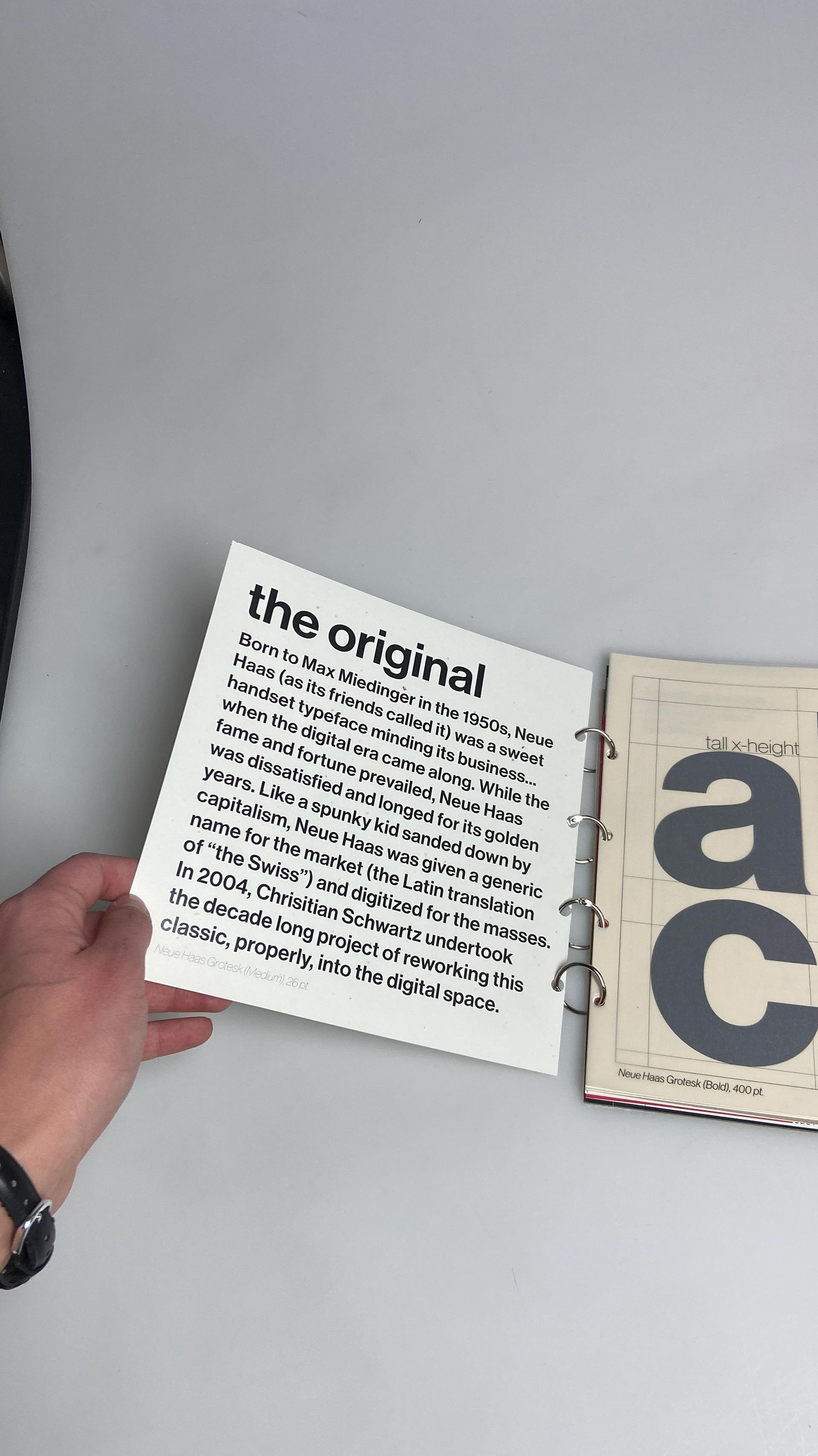 Neue Haas Grotesk backstory on off-white cardstock.
