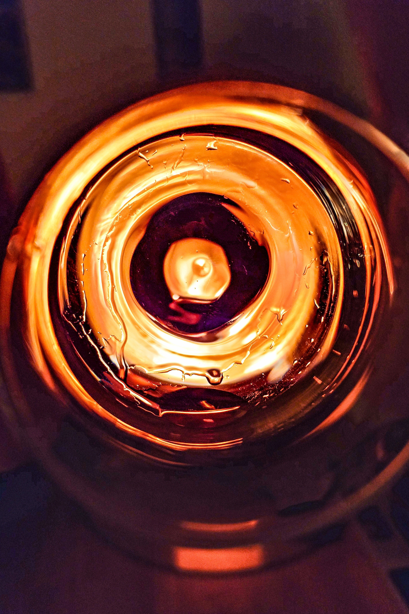 Blick von oben in ein leeres Glas. Alles Licht in dieser Aufnahme stammt vom Widerschein eines Kaminfeuers