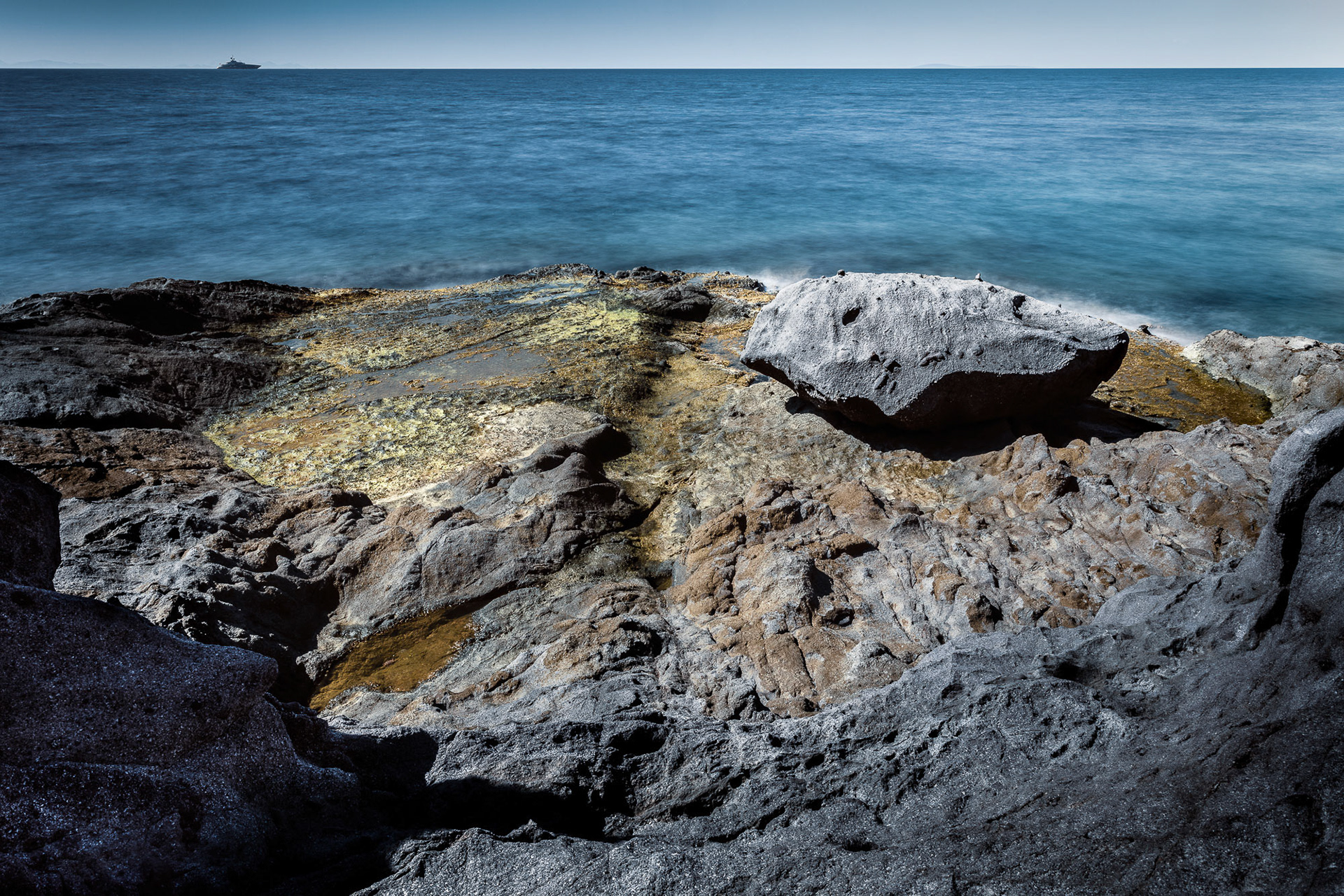 "Golden Rock" - Many different elements make up this image. The large rock is at the golden section. The curved line in the middle divide the two plateaus which have contrasting textures. The curve of the gray rock in the foreground create enclosure. The Mediterranean Sea and the yacht complete the background.